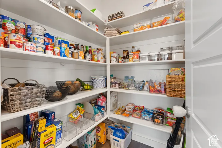 Walk-in pantry featuring white shiplap walls and multi-level built-in shelving