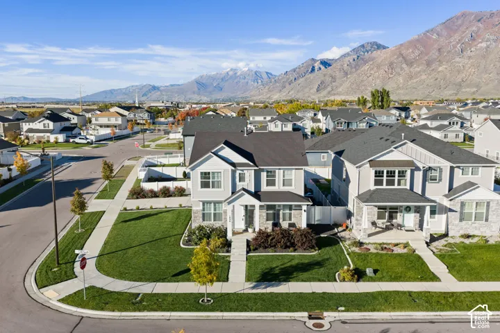 Corner lot residence featuring a two-story architectural design, stone veneer siding, covered front porch, and mountain backdrop