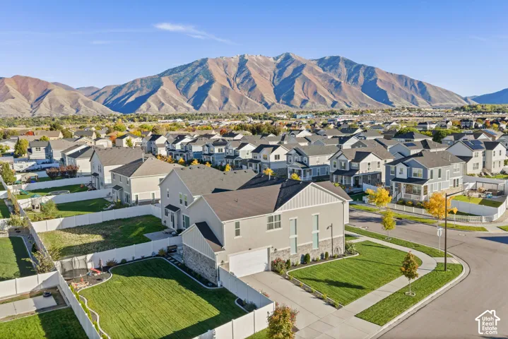 Two-story residence featuring a stone and siding exterior, attached two-car garage, fenced backyard, and concrete driveway, set against a prominent mountain backdrop