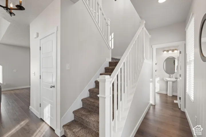Staircase featuring a white balustrade, wood-finish flooring, and neutral wall tones