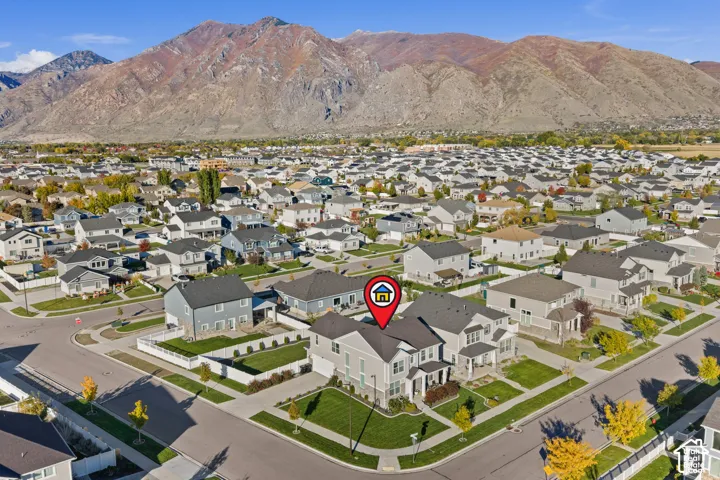 Two-story residence featuring a shingled roof, neutral siding, an attached garage, and a manicured corner lot situated against a mountain backdrop