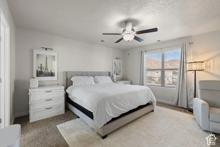 Neutral-toned interior featuring carpeted flooring, a ceiling fan with integrated lighting, and a large window with mountain scenery