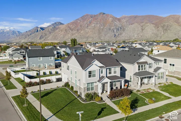 Two-story residence featuring a combination of horizontal siding and stone veneer, asphalt shingle roofing, and a front-facing covered porch, set against a prominent mountain backdrop