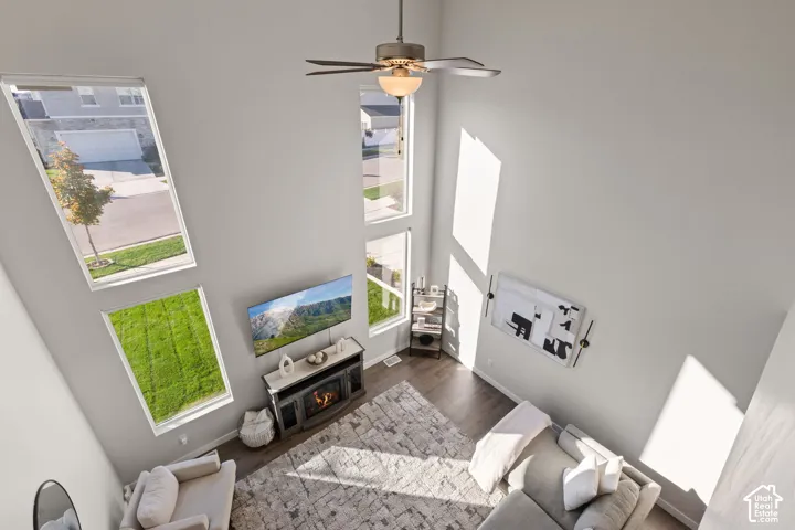 Double-height ceilings, floor-to-ceiling windows, wood-finish flooring, and a ceiling fan
