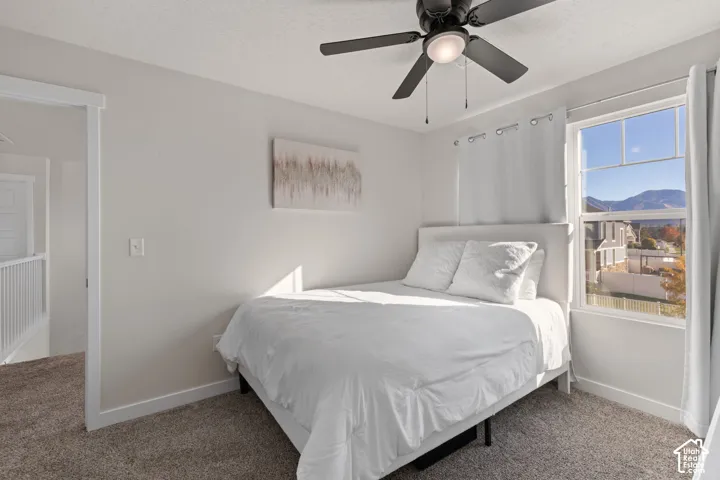 Neutral-toned interior featuring wall-to-wall carpeting, a ceiling fan with integrated lighting, and a single-hung window with a mountain backdrop