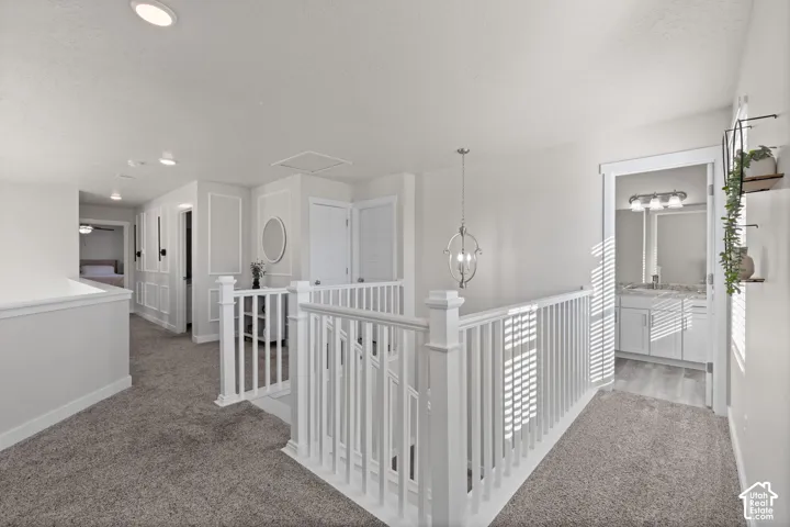 Open loft area featuring white wainscoting, a painted wood balustrade staircase, a circular wall mirror, and a globe-style pendant light fixture