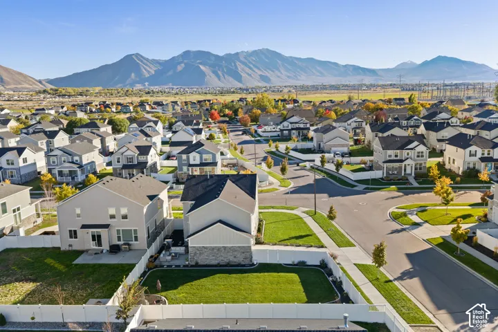Aerial perspective of a suburban neighborhood featuring extensive mountain backdrops, residential streets, manicured lawns, and white perimeter fencing
