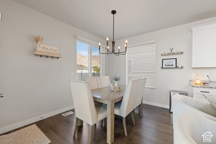 Dining area featuring wood-finish flooring, a contemporary six-arm chandelier, and sliding glass doors with mountain scenery