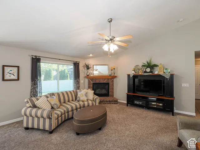 Family room area featuring a vaulted ceiling, brick fireplace with a wood mantel, and large windows