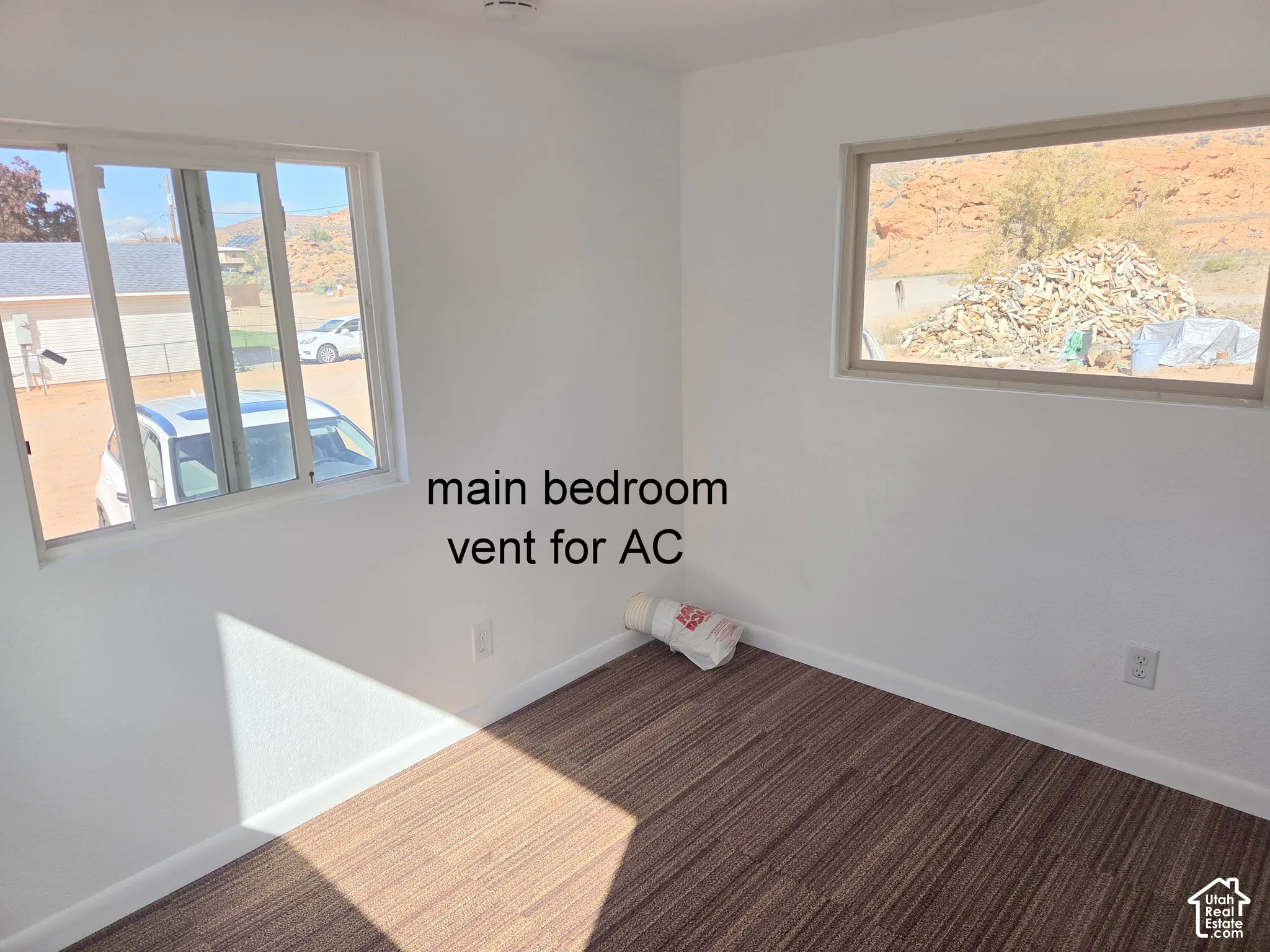 Room featuring white walls, neutral-toned striped flooring, and multiple windows