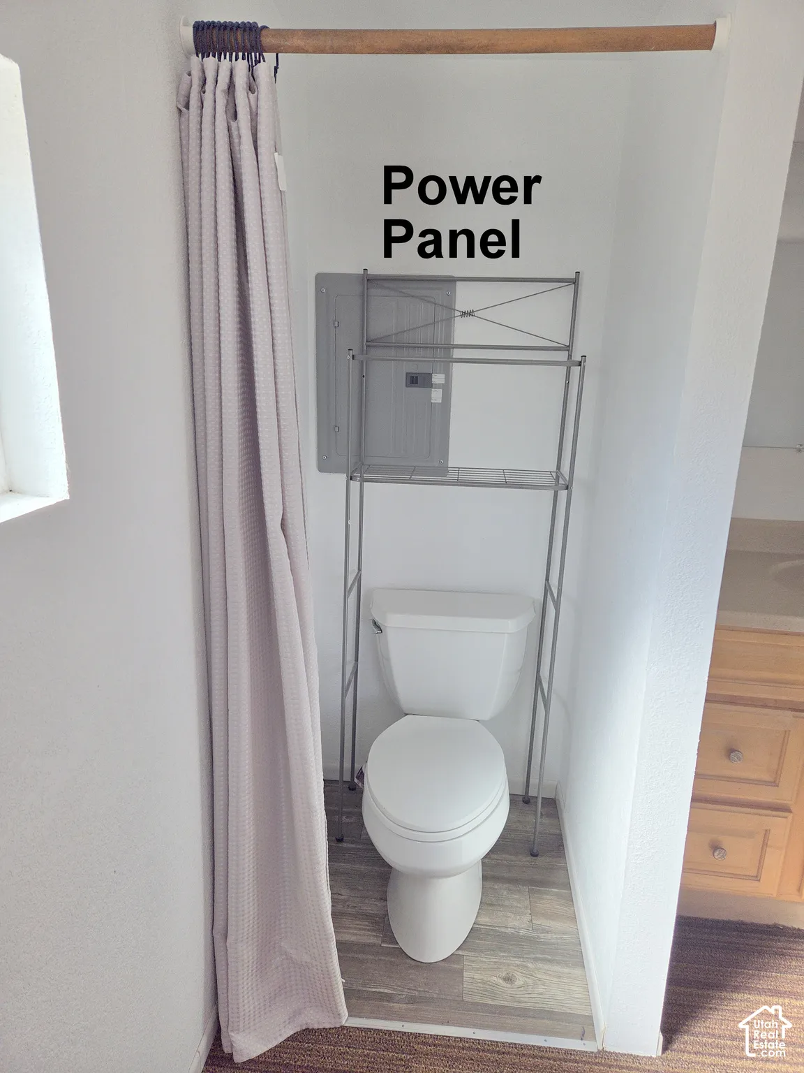 Recessed area featuring a porcelain toilet and wood-finish flooring