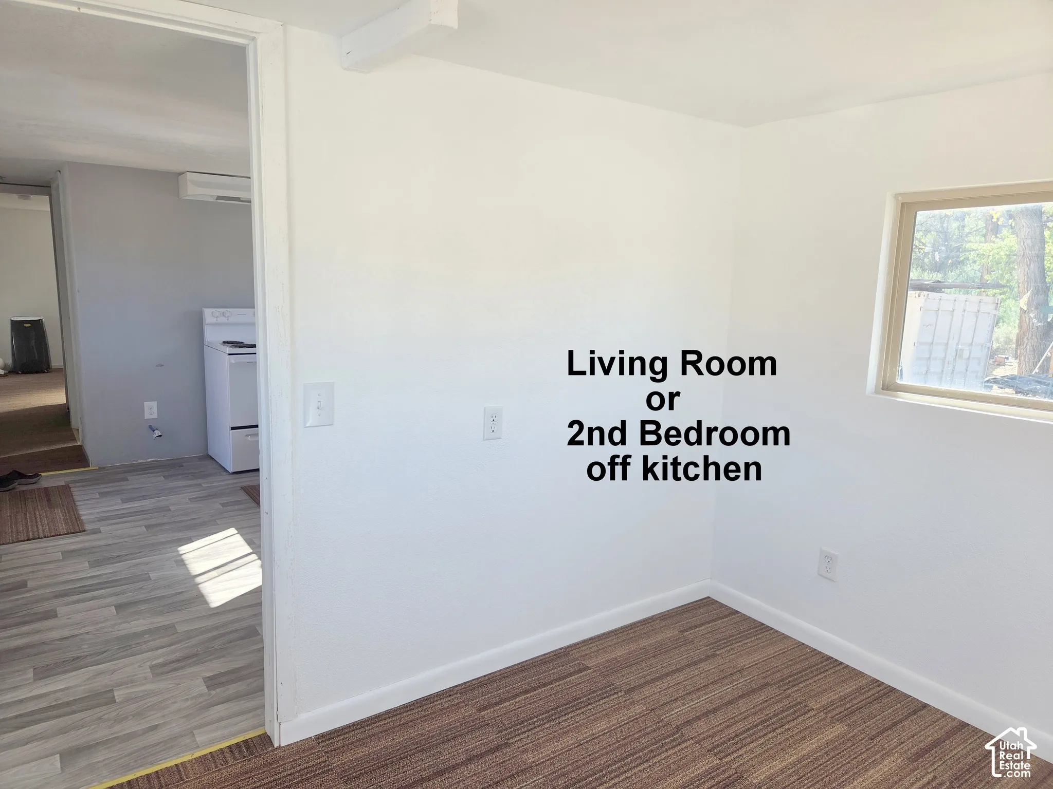Interior space featuring neutral wall paint, wood-finish flooring, and a single-pane window