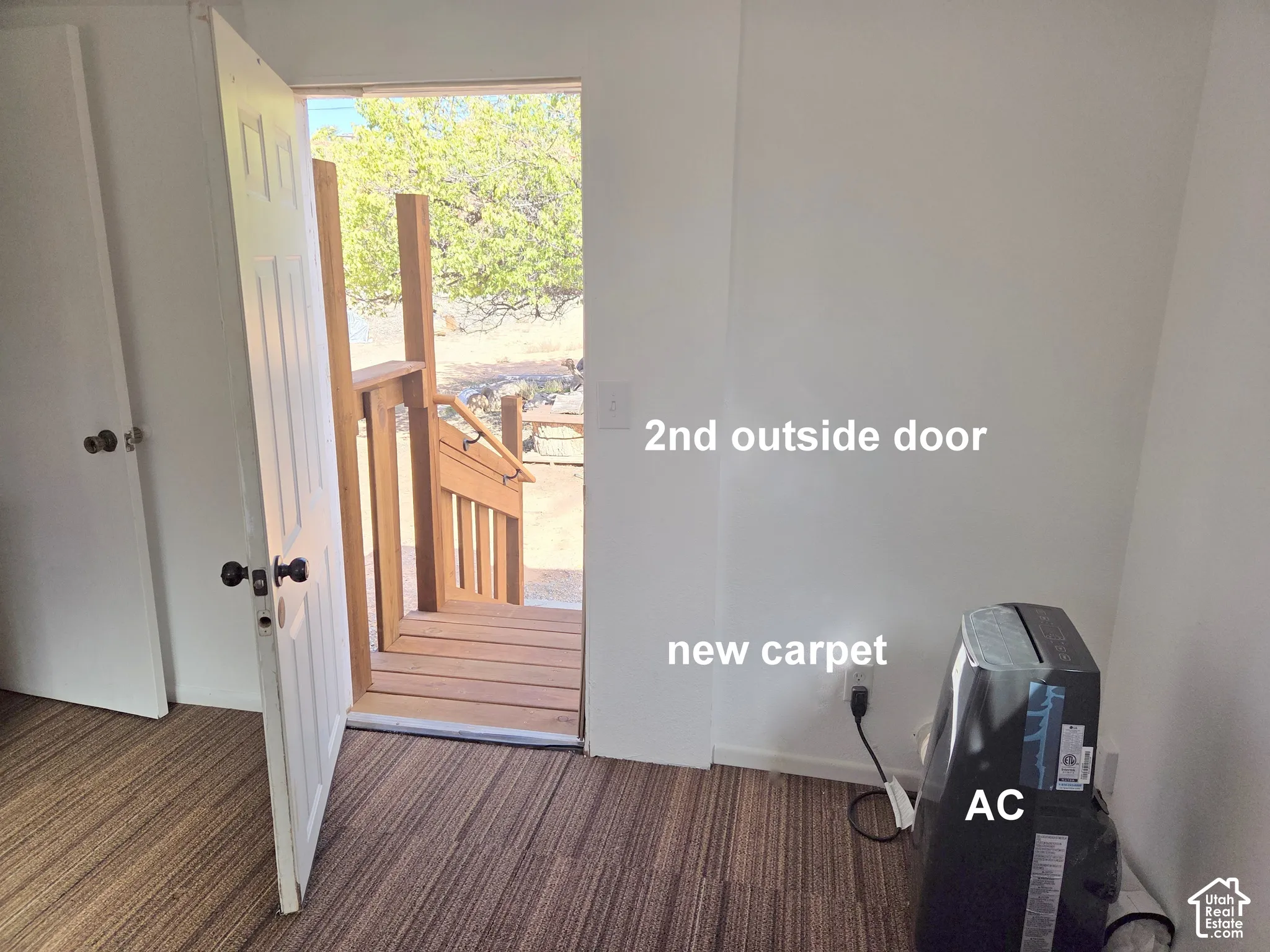 Interior space featuring striped carpeting and a doorway providing egress to a wooden deck