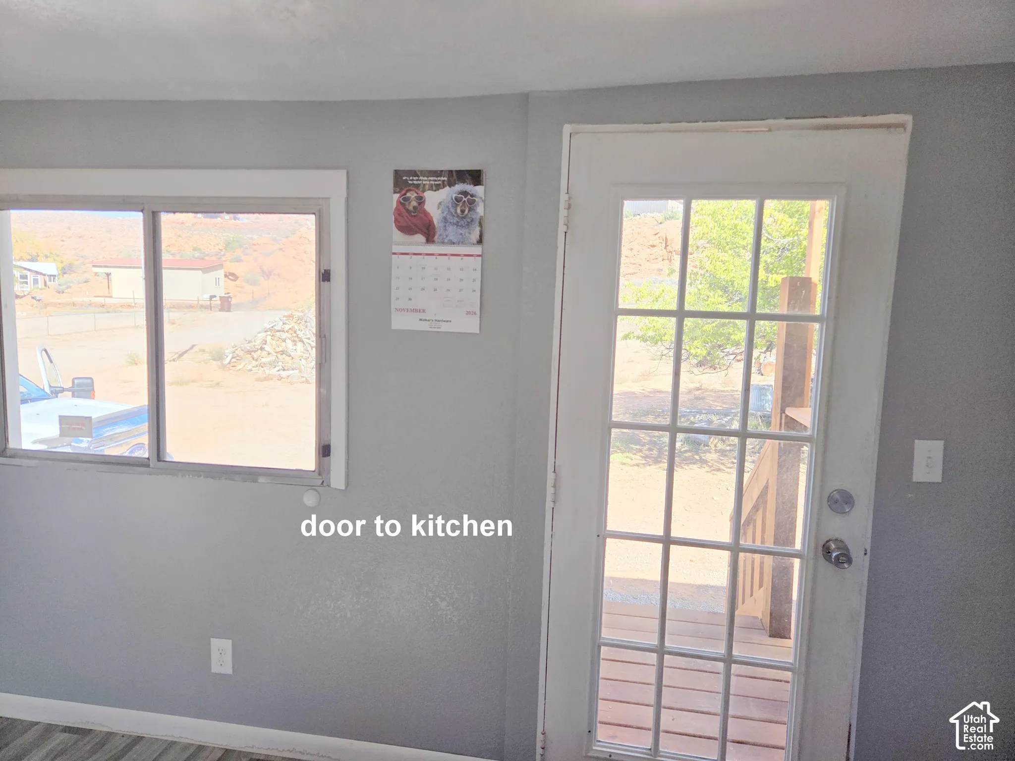 Full-lite glass door with a decorative grid pattern, sliding window, and neutral-toned wall finish