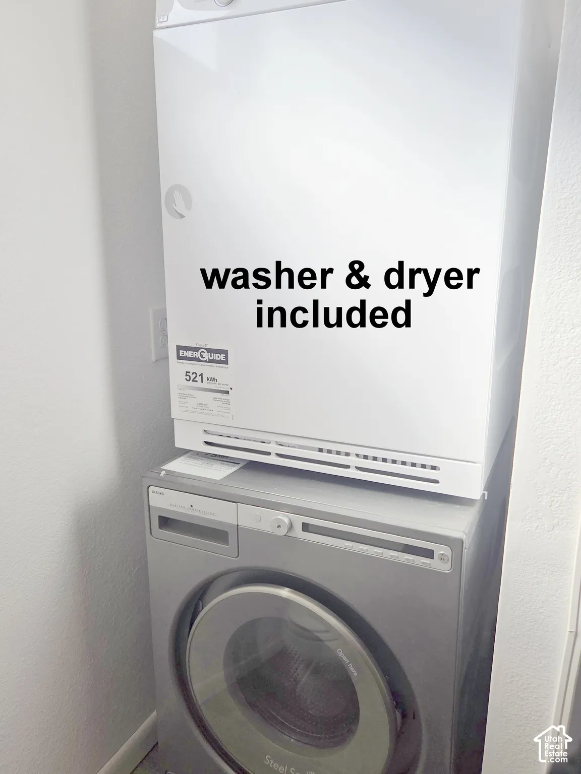 Stacked front-load laundry unit featuring a white electric dryer and a silver metallic washing machine