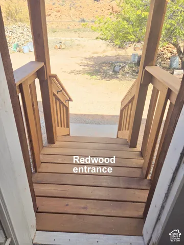 Stained wood landing featuring a matching timber railing, structural support posts, and a handrail