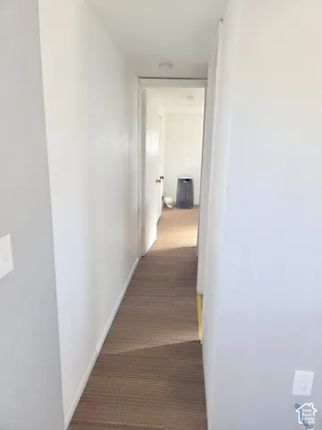 Hallway featuring neutral wall paint, wood-finish flooring, and recessed ceiling lighting