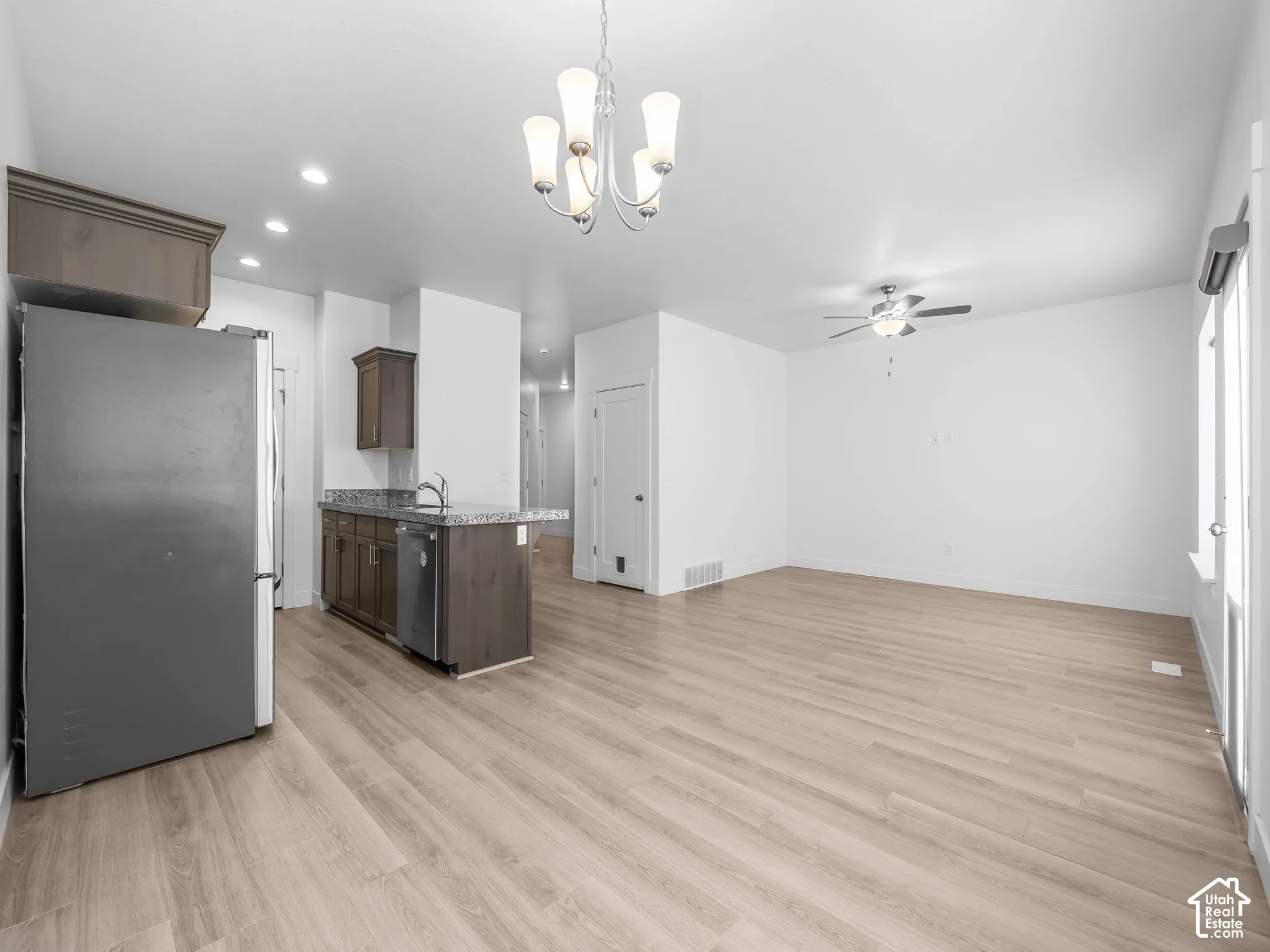 Kitchen featuring wood-finish cabinetry, stone-surface countertops, wood-finish flooring, recessed lighting, and a multi-light chandelier
