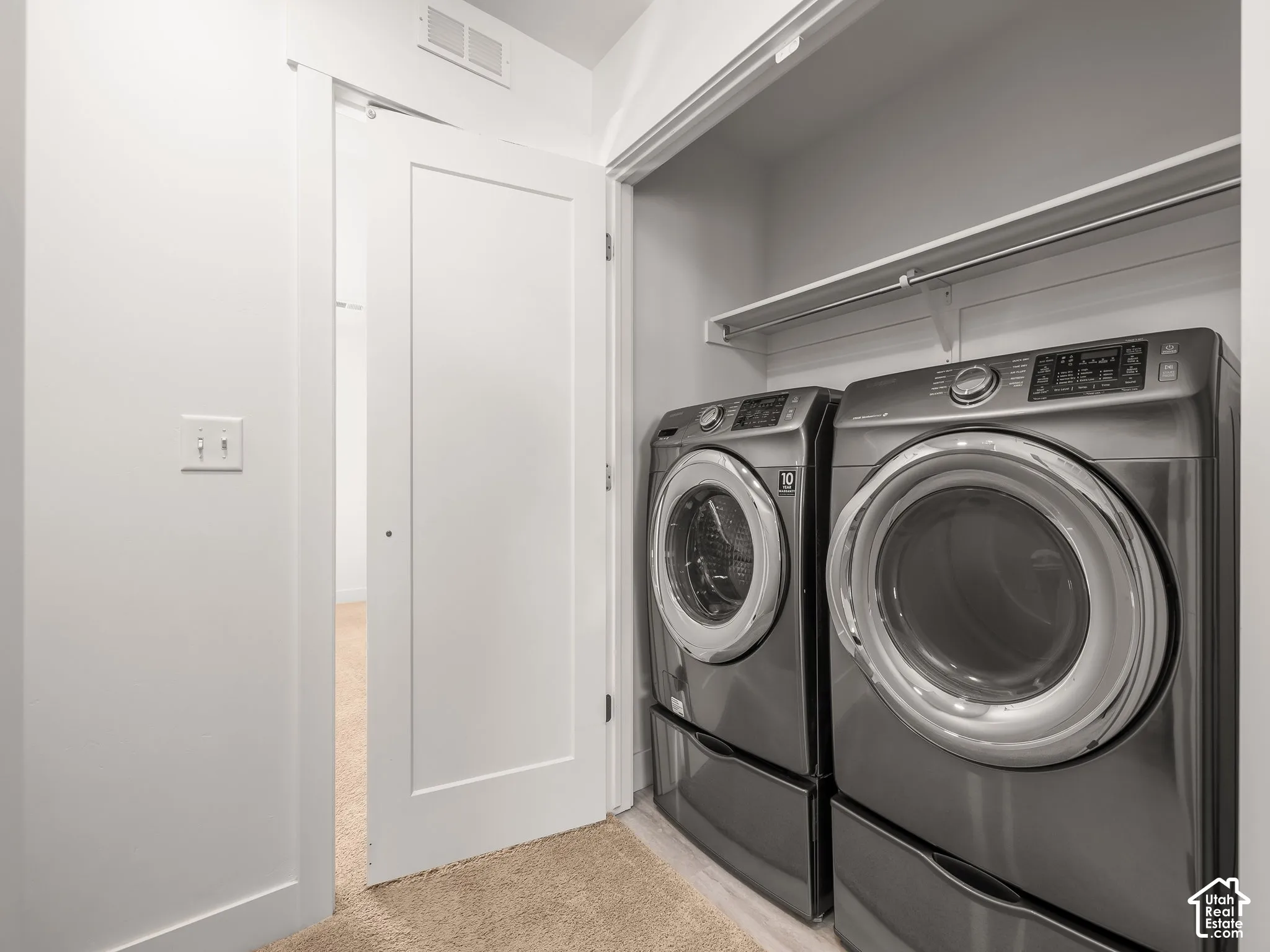 Dedicated laundry area featuring a white shaker-style door, built-in shelving, and integrated clothing rod