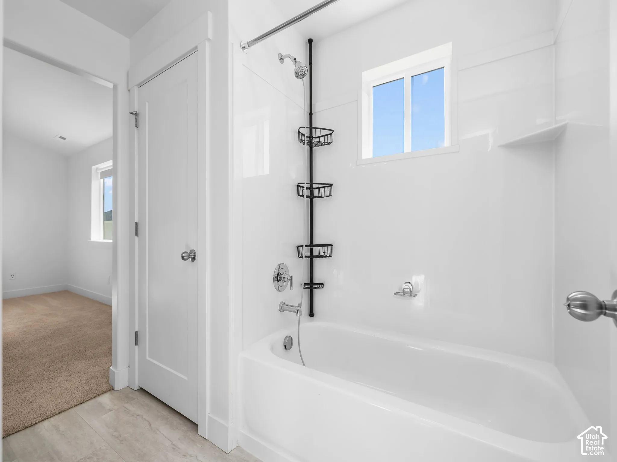 Full-height tub and shower surround with a built-in shelf, integrated slider window, chrome-finish plumbing fixtures, and solid-core interior door