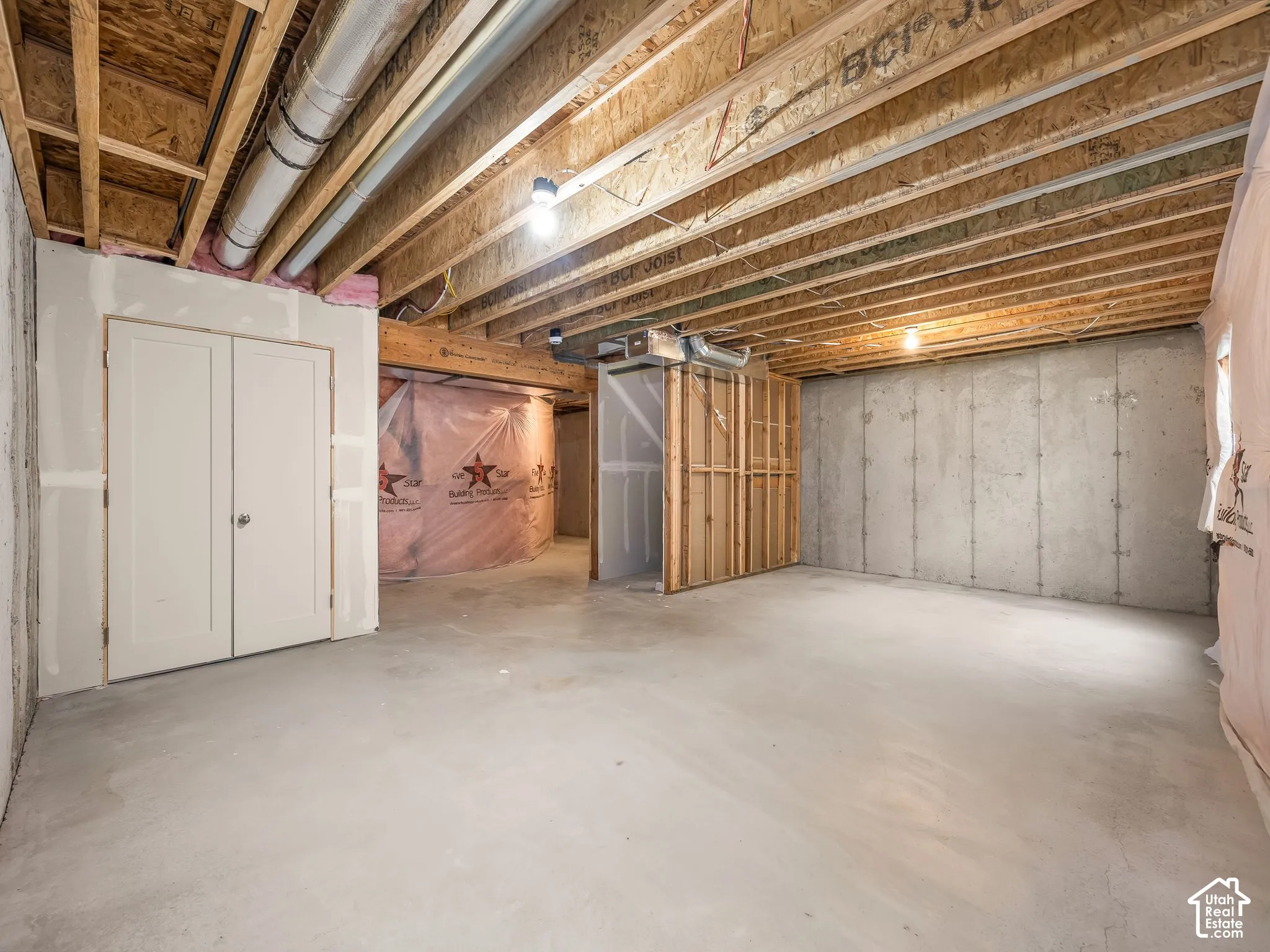 Unfinished basement featuring exposed wood-beam ceiling, concrete flooring, concrete foundation walls, and double-door closet storage