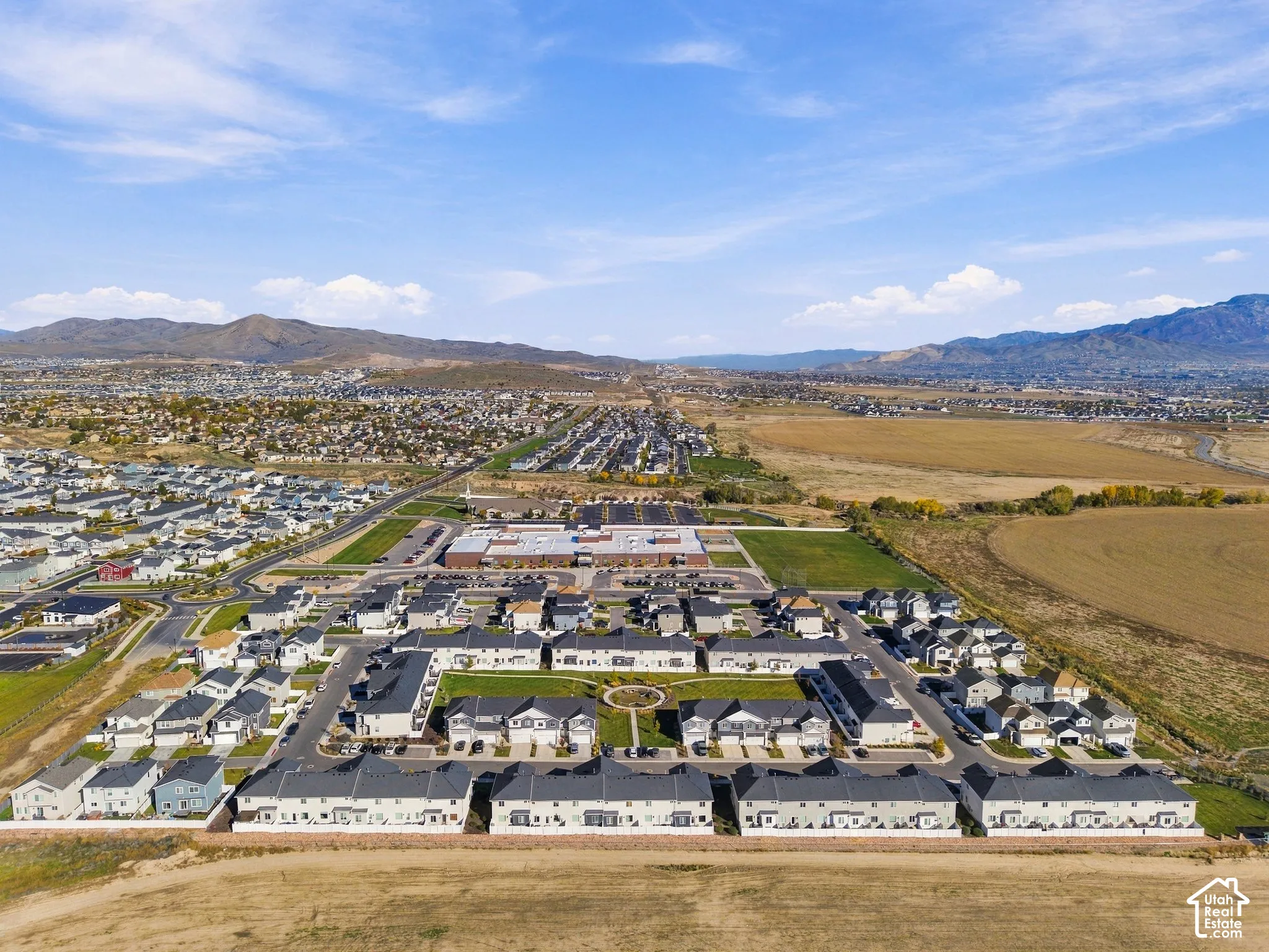 Aerial perspective of multi-family residential structures featuring shingled rooflines, exterior siding, and a central landscaped courtyard with paved walkways, set against a backdrop of mountain ranges