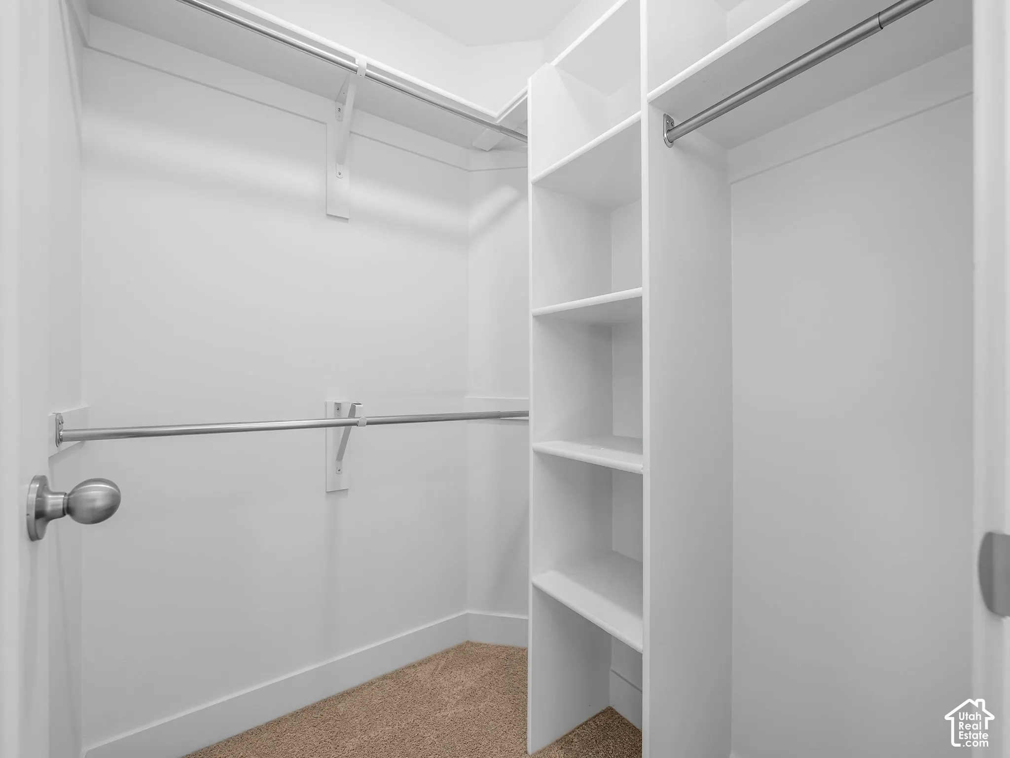 Walk-in closet featuring white built-in shelving, dual-level metal hanging rods, and neutral carpeting