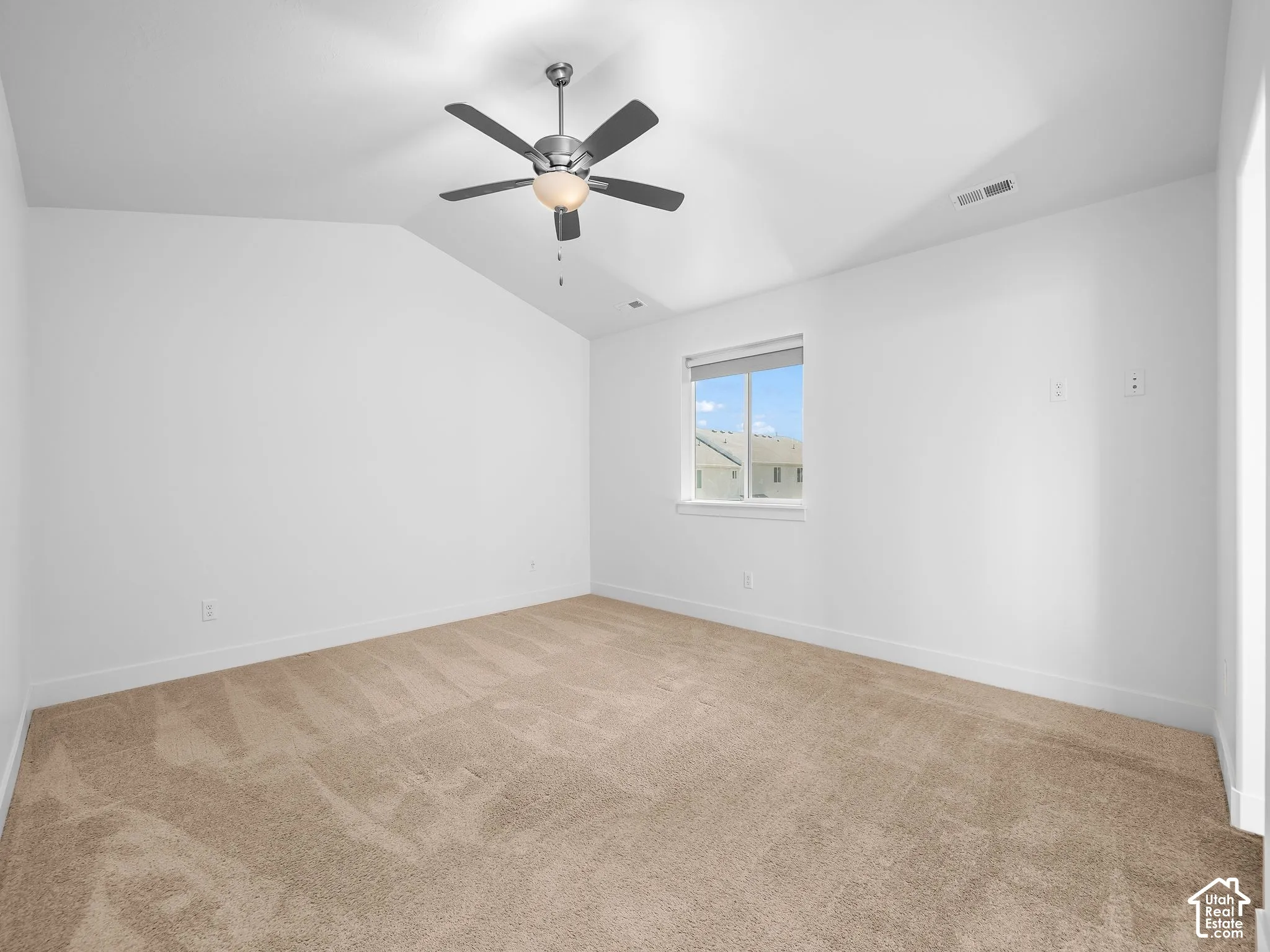 Vaulted ceilings, neutral carpeting, and a central ceiling fan with integrated lighting