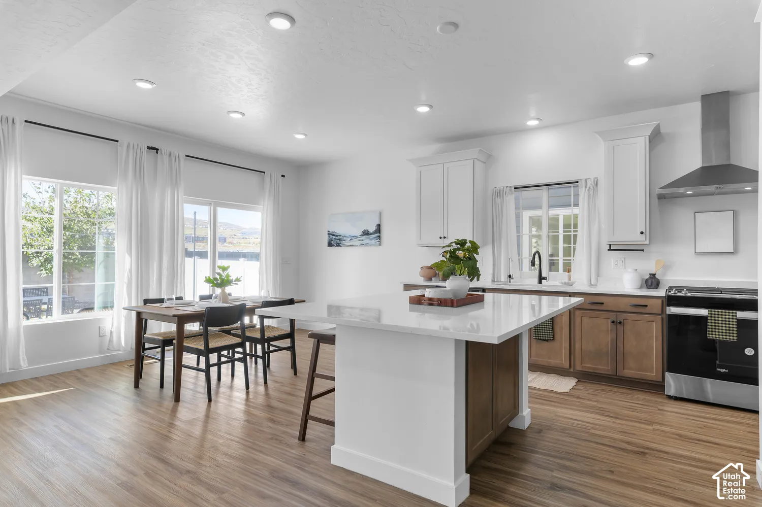 Kitchen featuring a central island with a solid surface countertop, white shaker-style cabinetry, stainless steel range hood, and wood-finish flooring