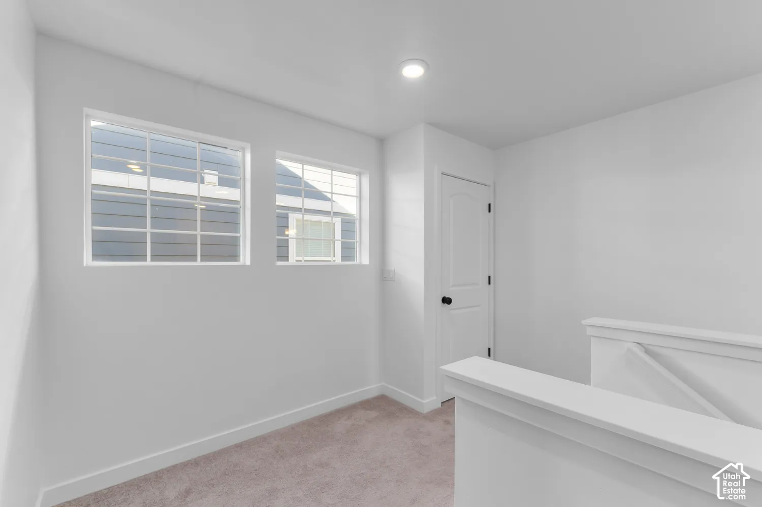 Neutral-toned wall-to-wall carpeting, dual windows with grid detailing, recessed ceiling lighting, and a paneled interior door