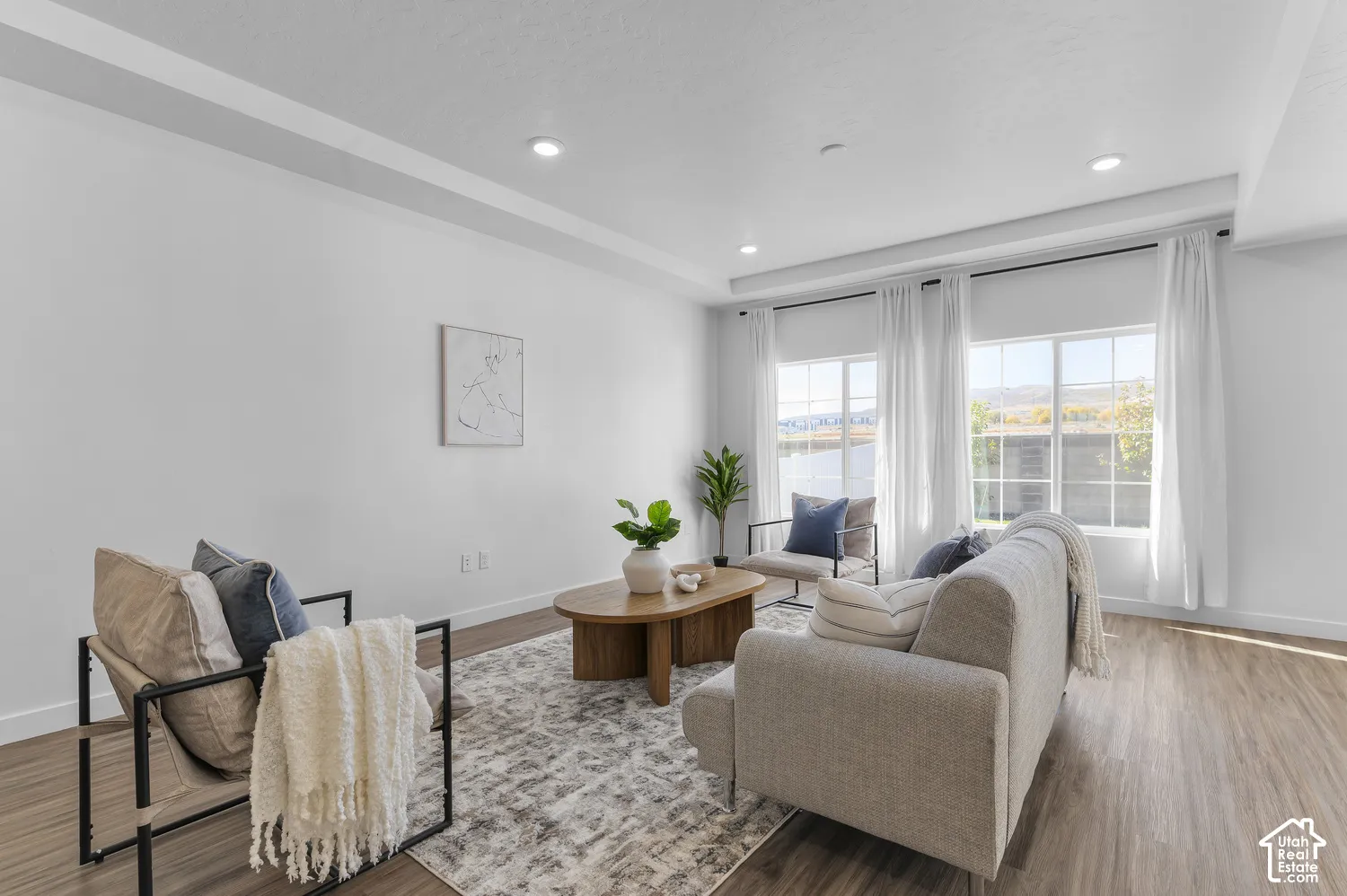 Room featuring tray ceilings, recessed lighting, wood-finish flooring, and large windows with muntins