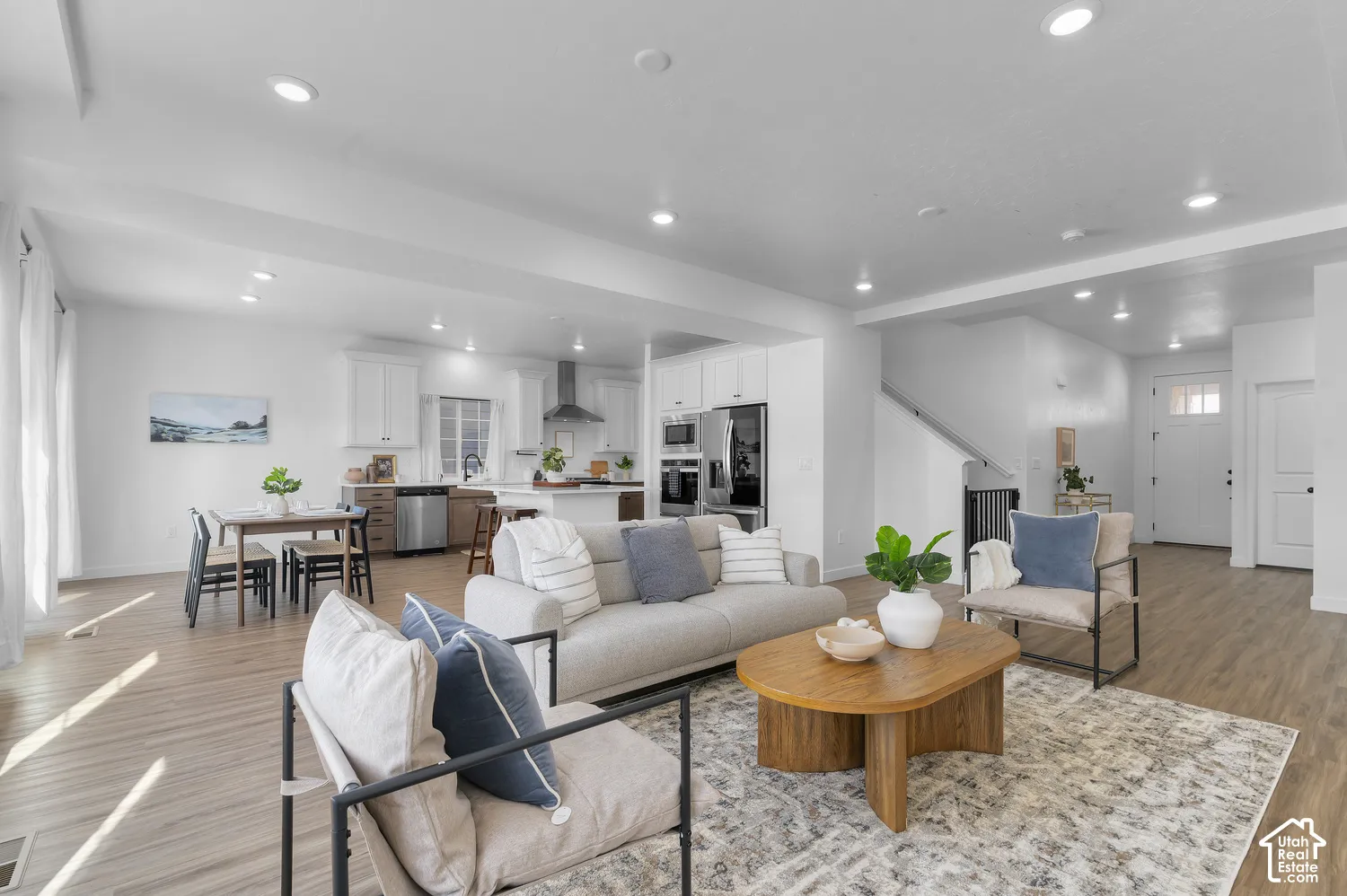 Open-concept floor plan featuring wood-finish flooring, recessed lighting, white cabinetry, and stainless-steel appliances