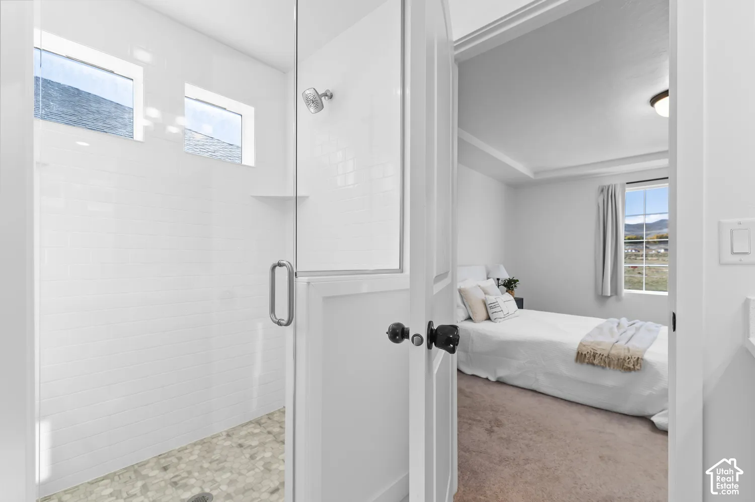 Walk-in shower featuring white subway tile surround, pebble-style stone flooring, and a glass door enclosure