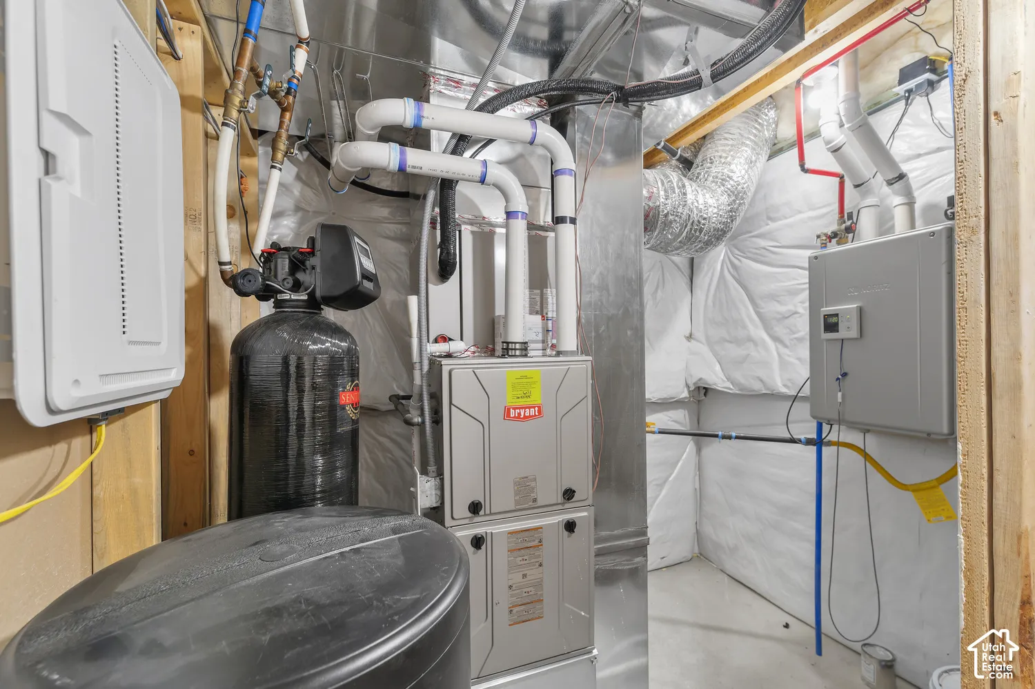 Mechanical area featuring a Bryant furnace, high-efficiency water filtration system, tankless water heater, and foil-faced wall insulation