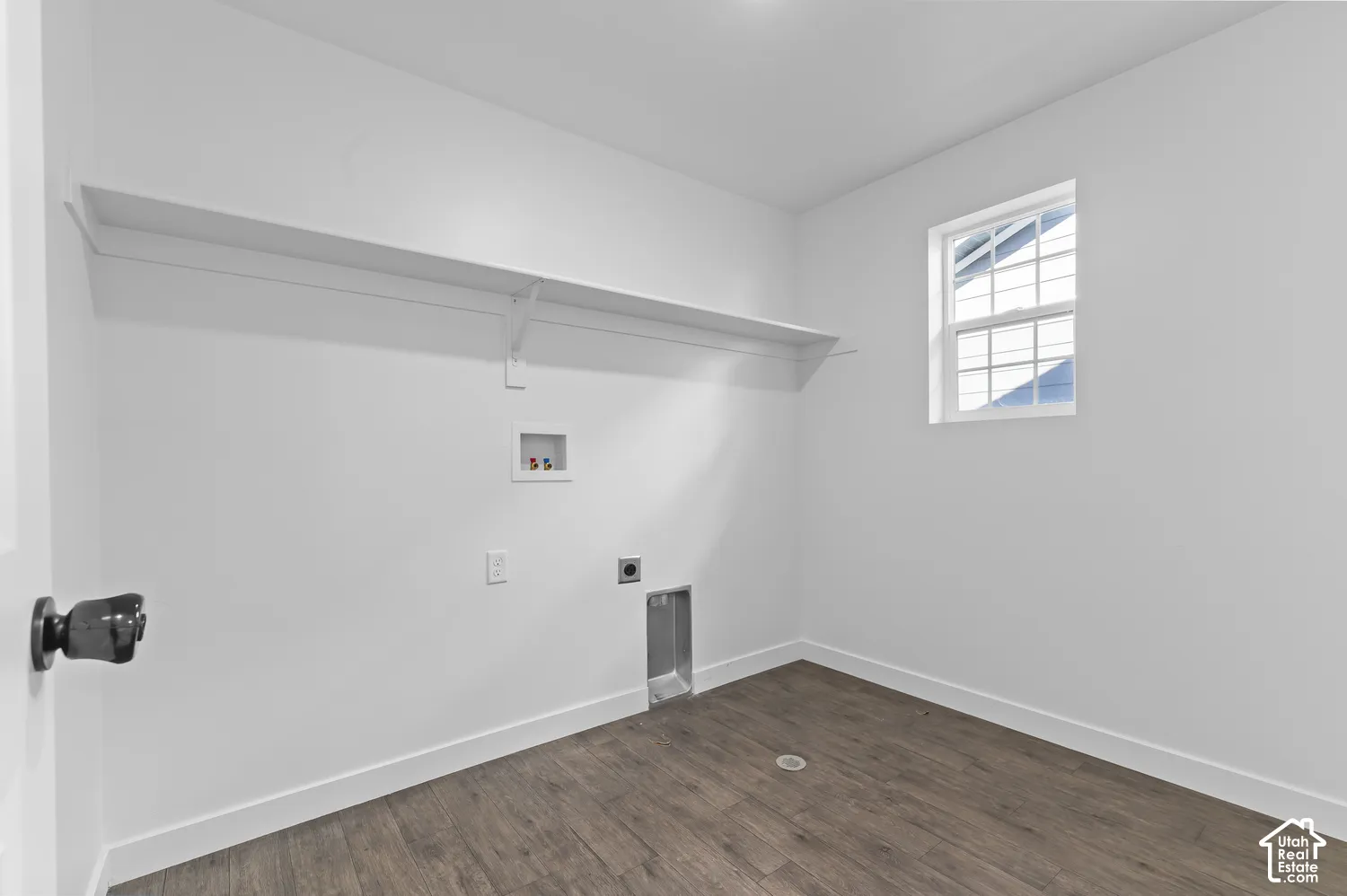 Utility room featuring wood-finish flooring, a wall-mounted shelf, and a single-pane window
