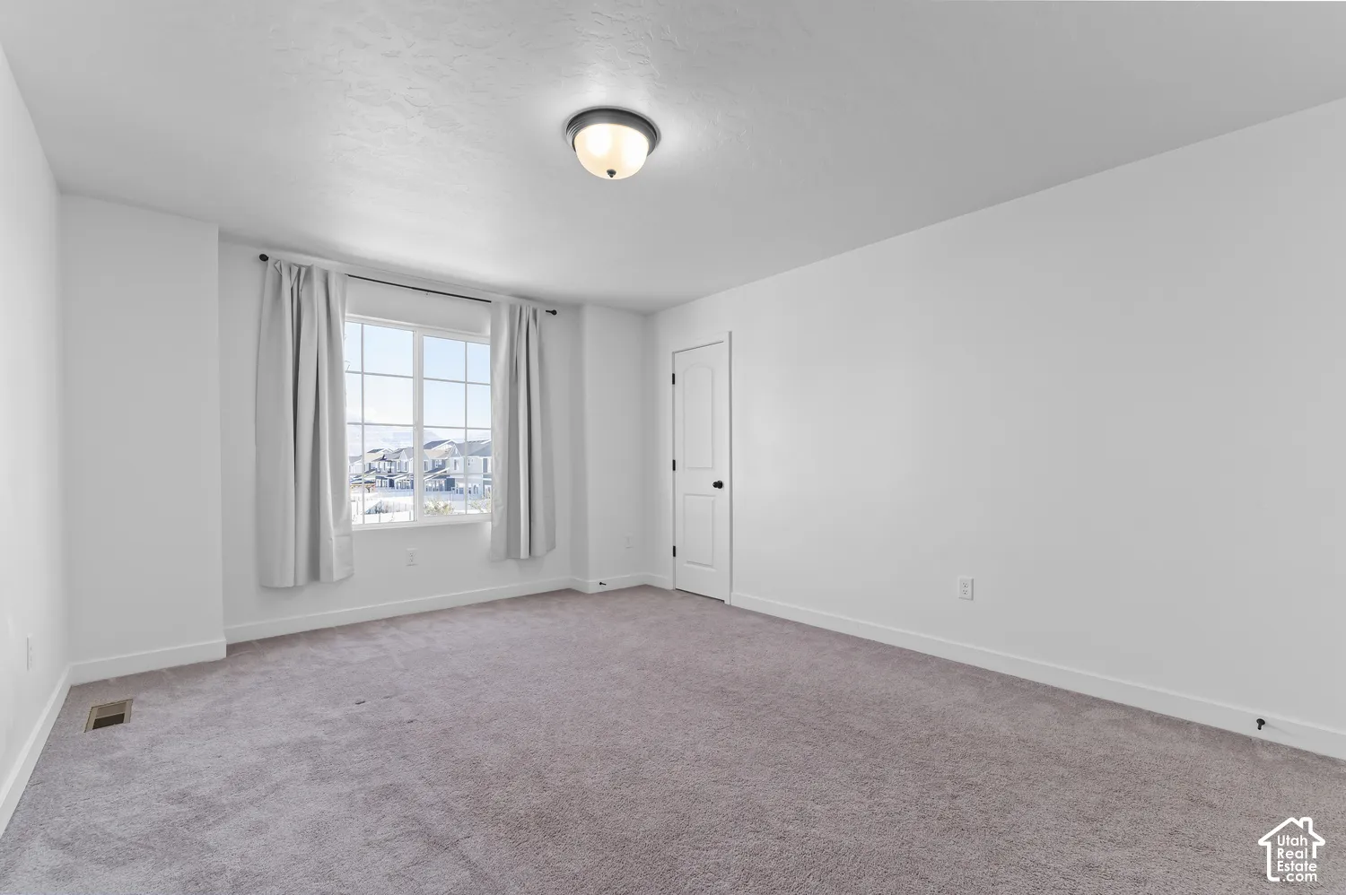 Neutral-toned carpeting, multi-pane window with exterior scenery, flush-mount dome lighting, and solid-core interior door