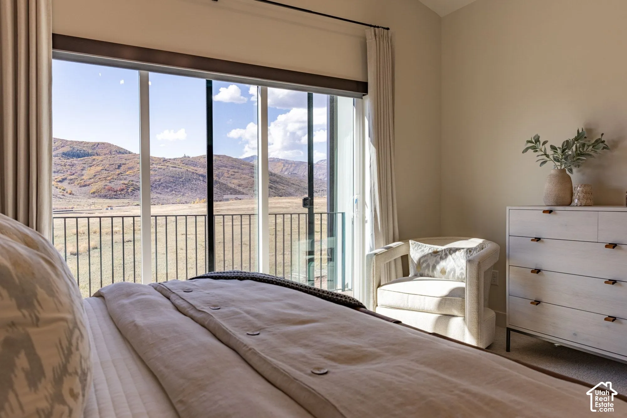 Floor-to-ceiling sliding glass door, metal balcony railing, and vaulted ceiling, with mountain backdrop