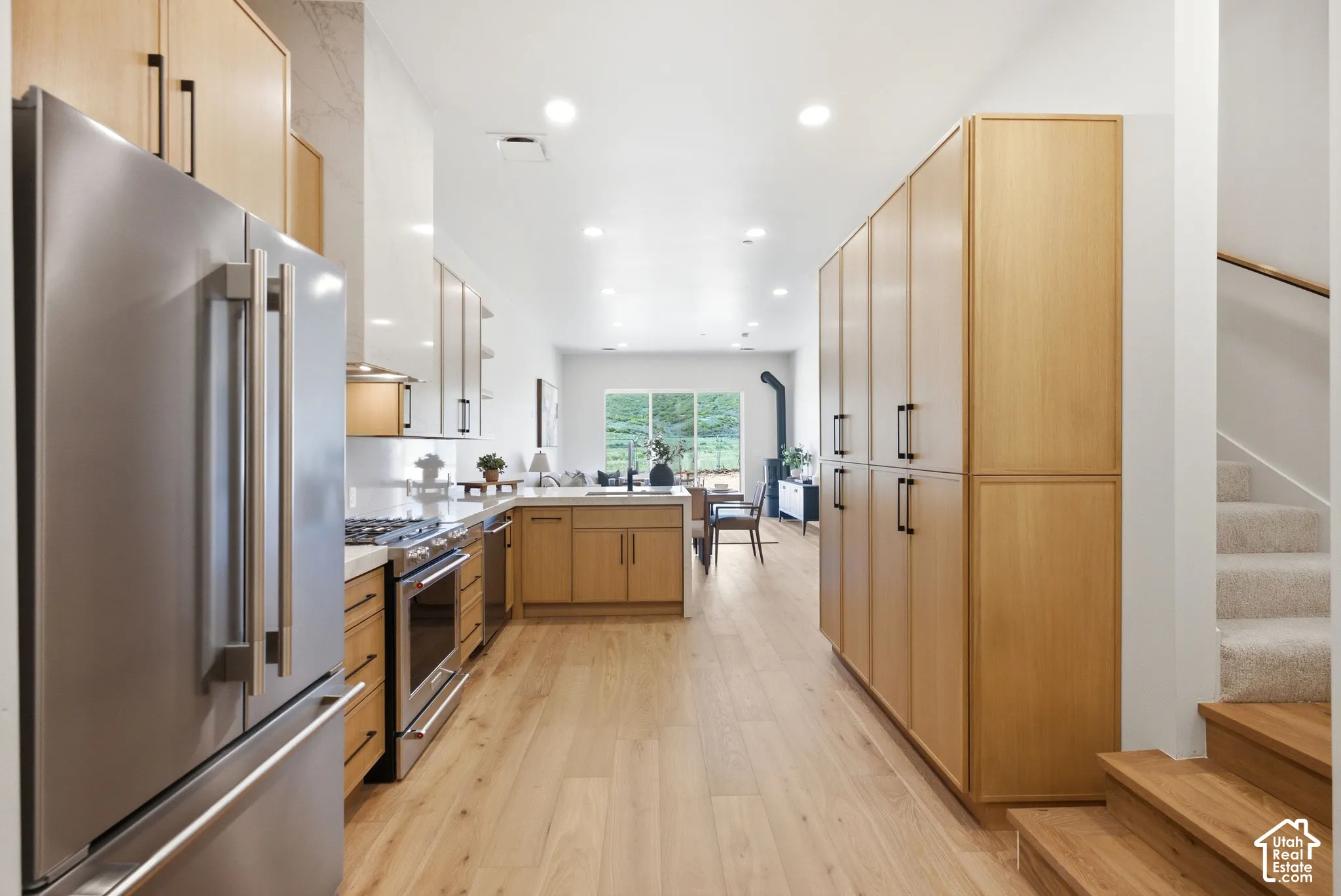 Kitchen featuring light-tone wood cabinetry, stainless steel appliances, recessed lighting, and wood-finish flooring