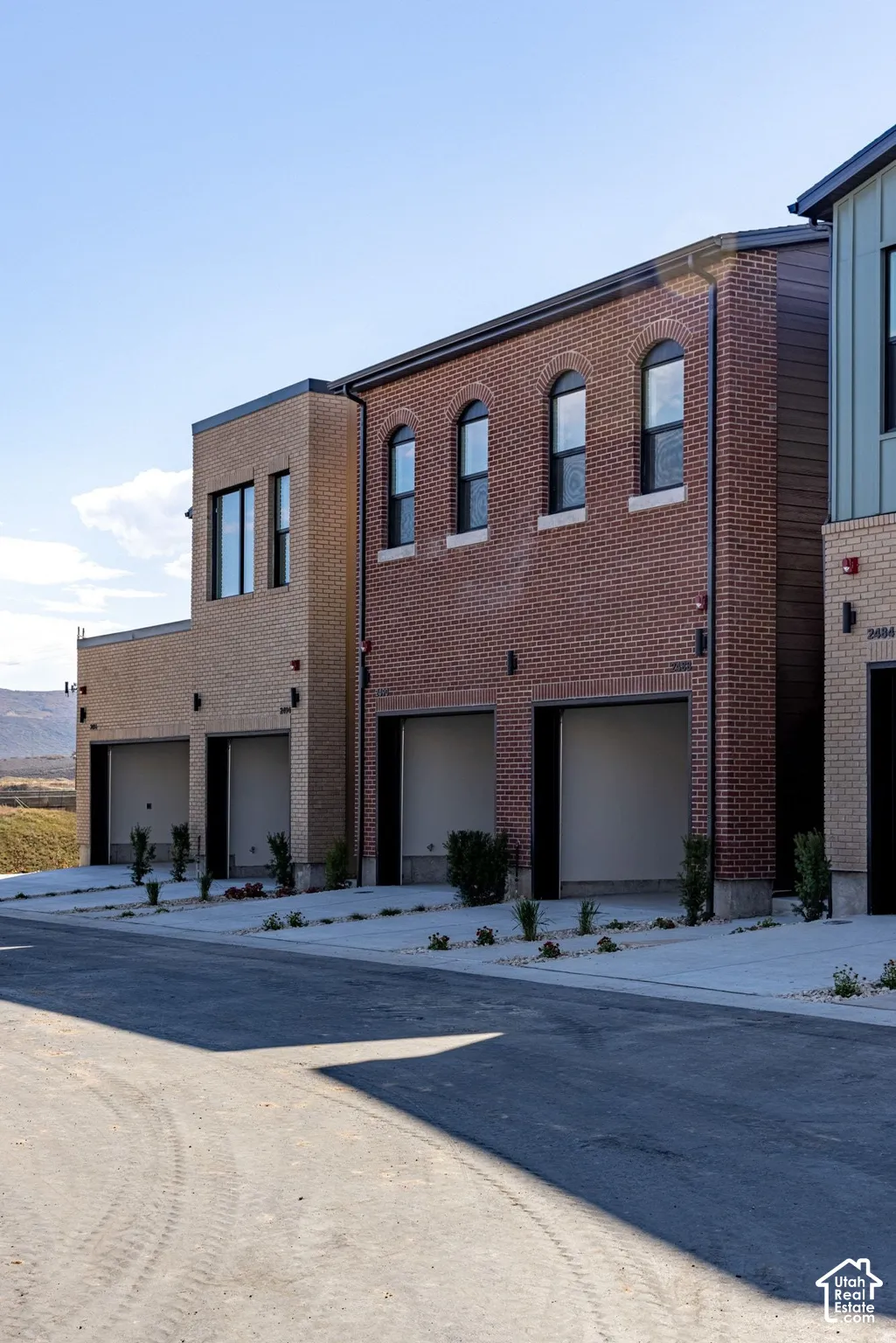 Exterior facade featuring multi-tone brick masonry, arched window detailing, and individual multi-car garage access