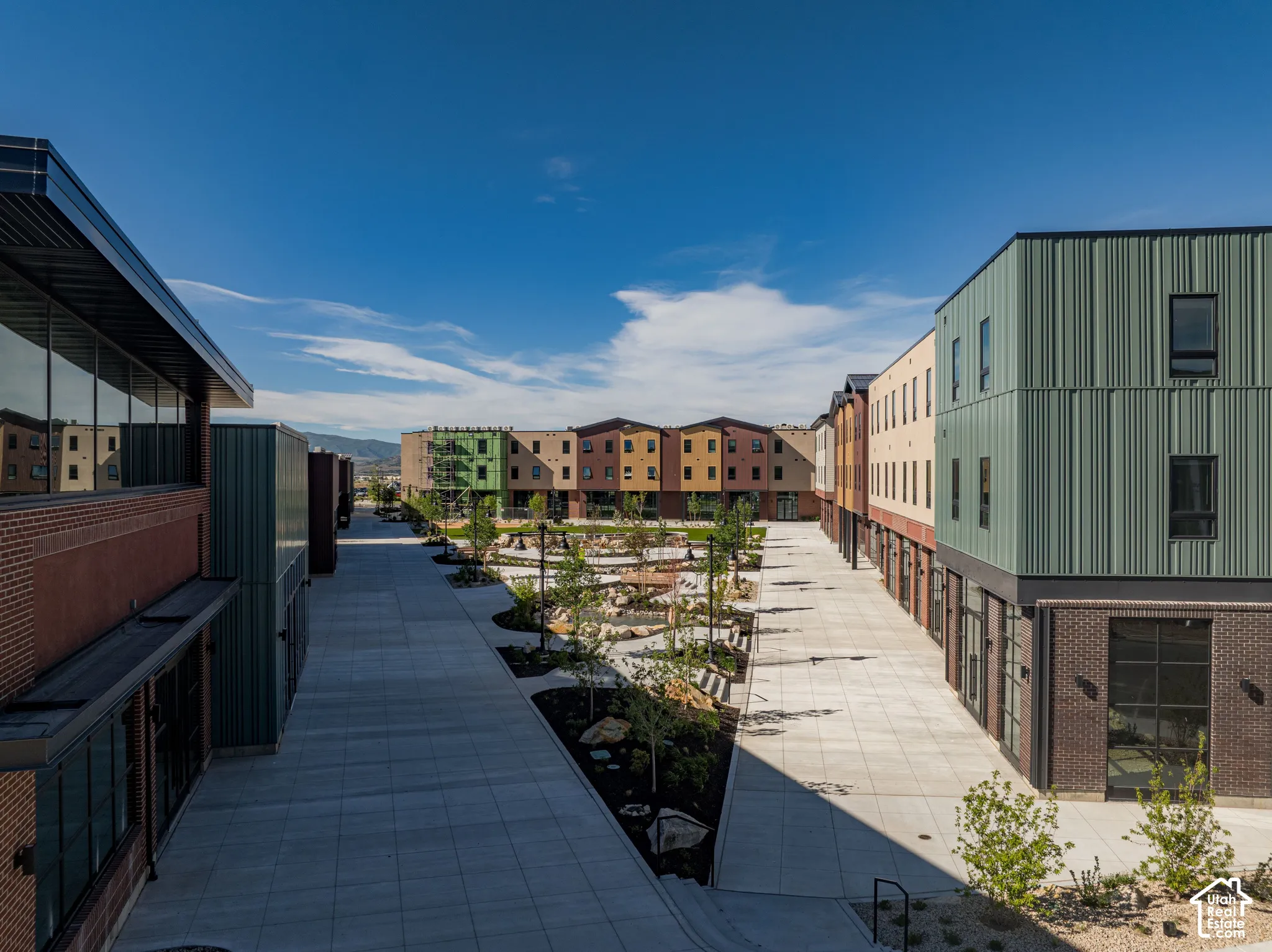 Multi-story structures featuring mixed-media siding, brick masonry base levels, expansive glazing, and an outdoor courtyard with landscaped hardscaping and stone features
