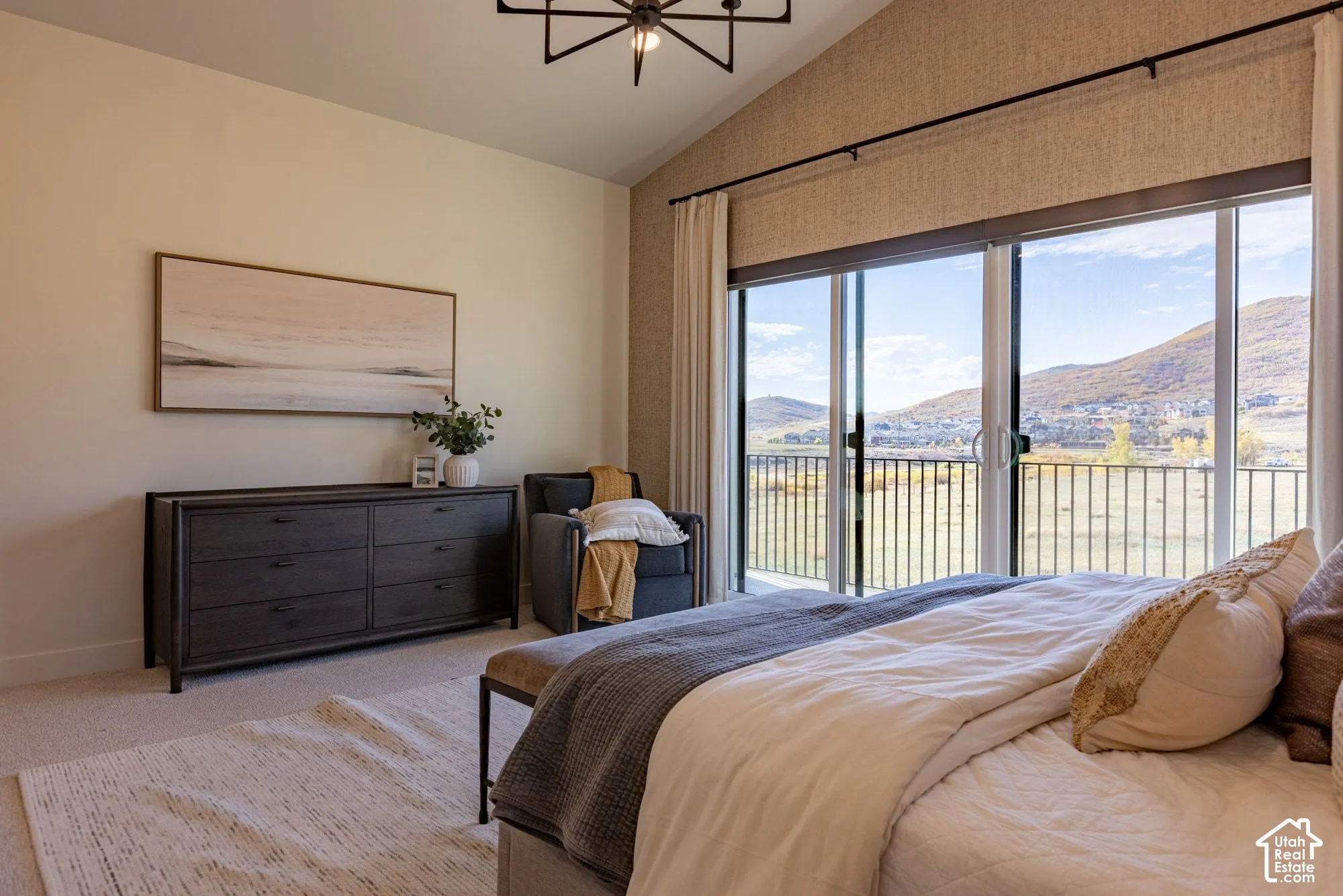 Vaulted ceiling, sliding glass doors with metal railing, textured accent wall, and mountain backdrop