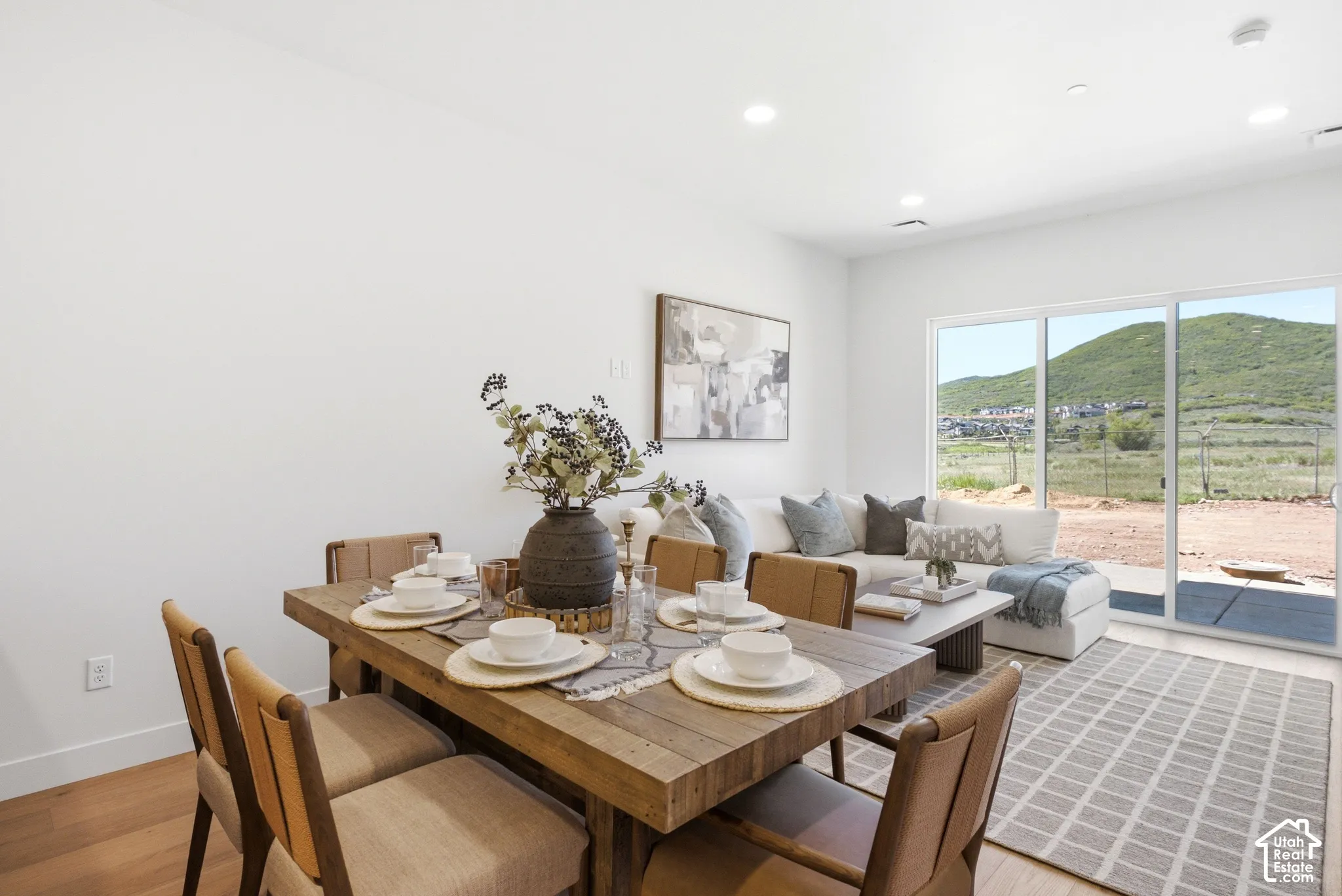 Open-concept space featuring recessed lighting, wood-finish flooring, and large sliding glass doors revealing mountain scenery