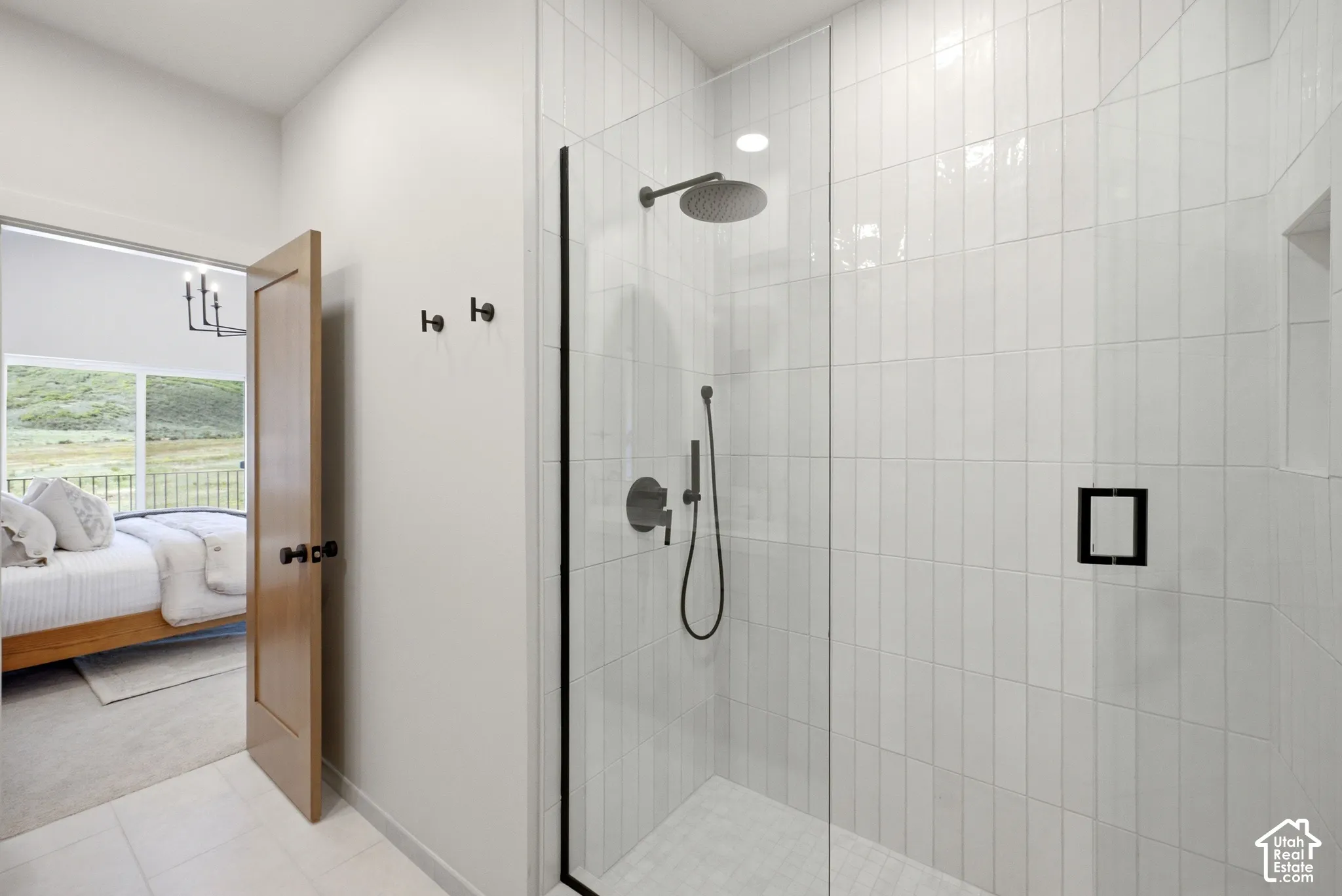 Walk-in shower featuring vertical white subway tile, a frameless glass enclosure, a rainfall showerhead, a hand-held sprayer, and matte black hardware