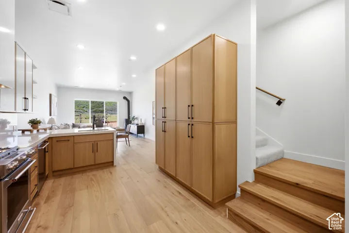 Kitchen featuring wood-finish cabinetry, floor-to-ceiling pantry storage, recessed lighting, and wood-finish flooring
