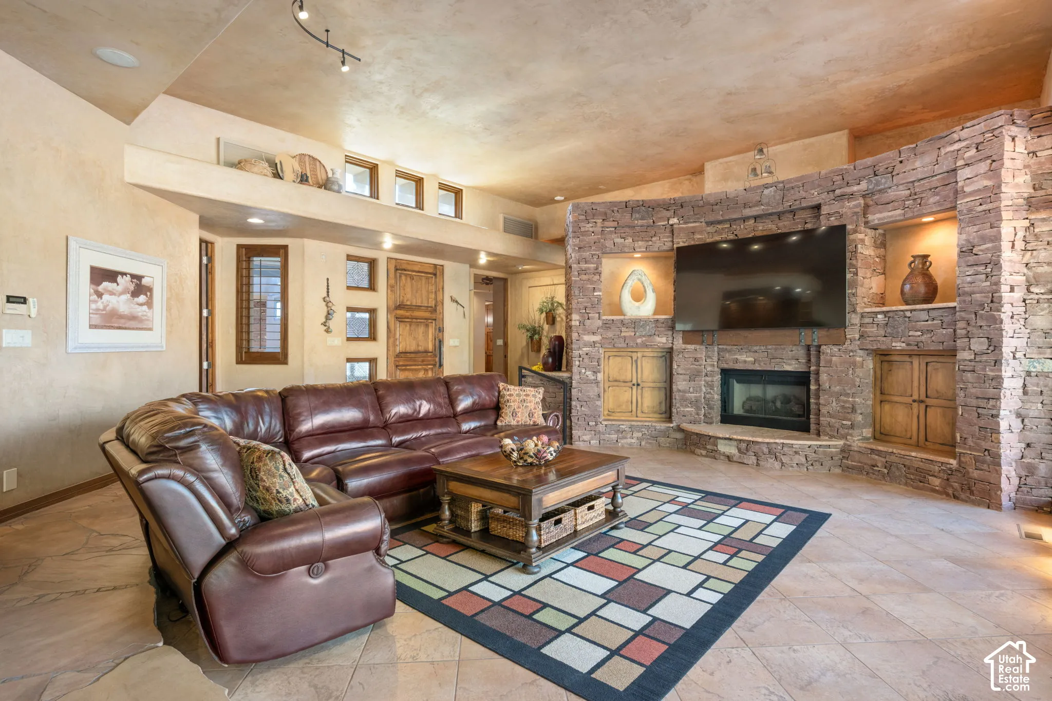 Curved stone accent wall featuring a recessed fireplace, custom built-in cabinetry, and integrated shelving, complemented by tile flooring and textured wall finishes