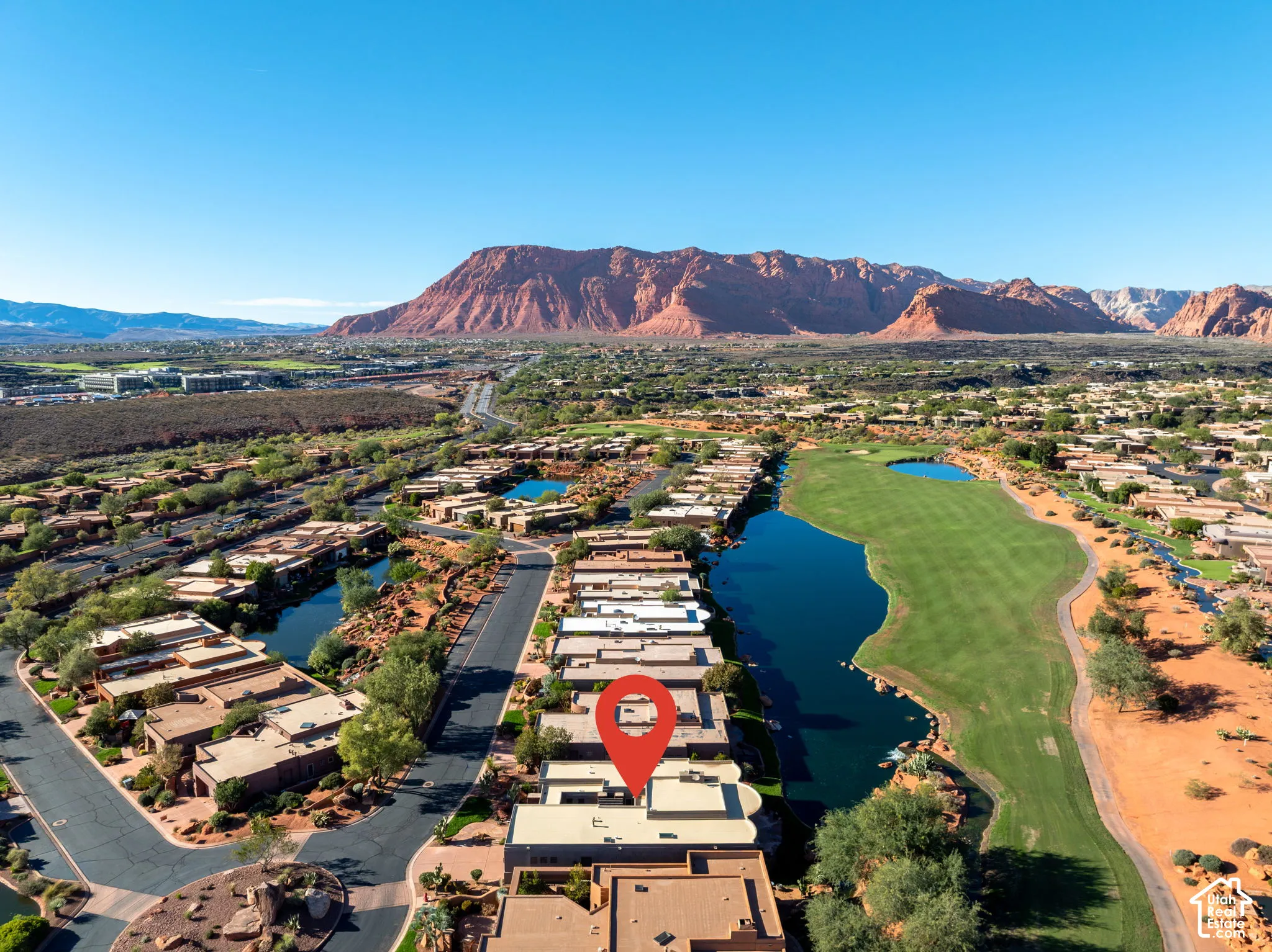 Aerial perspective showcasing a desert landscape with mountain backdrops, adjacent golf course fairways, water features, and regional road infrastructure