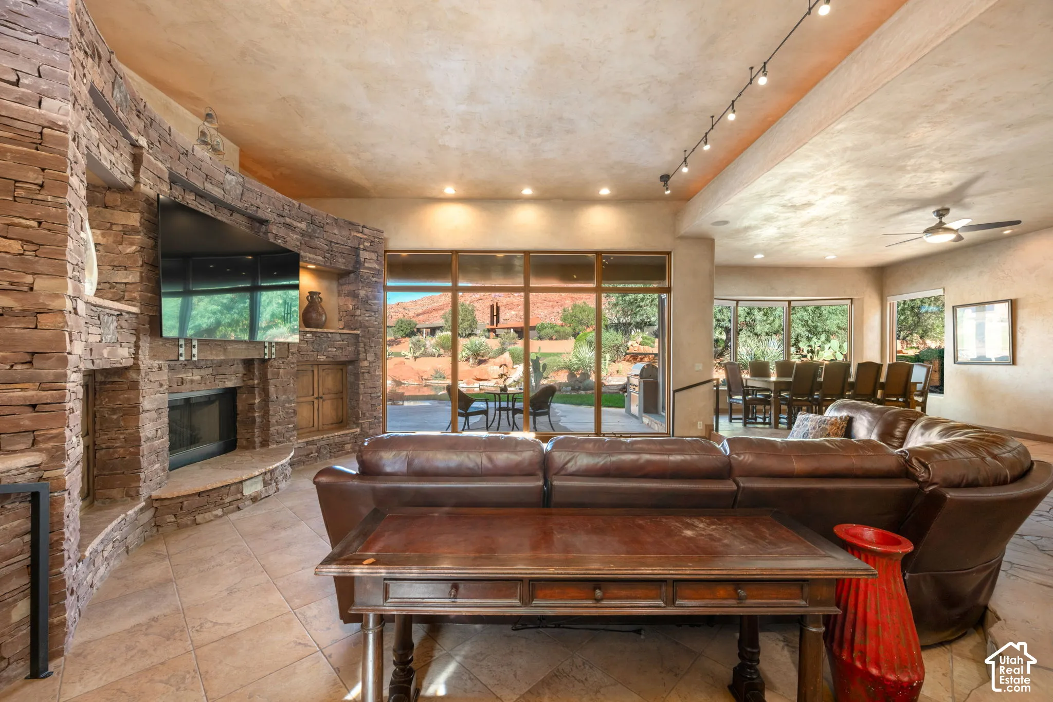 Curved, floor-to-ceiling dry-stack stone fireplace with integrated media alcoves and stone hearth, expansive window walls, and natural stone flooring