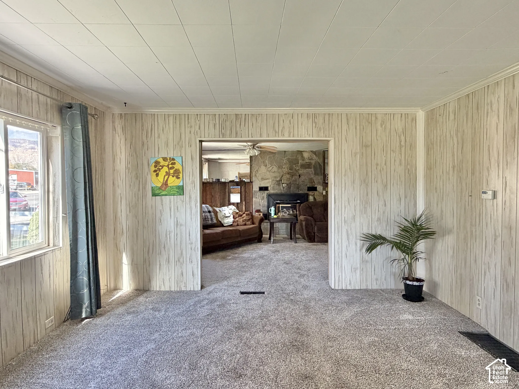 Paneled walls, textured ceiling, stone fireplace, and carpeted flooring