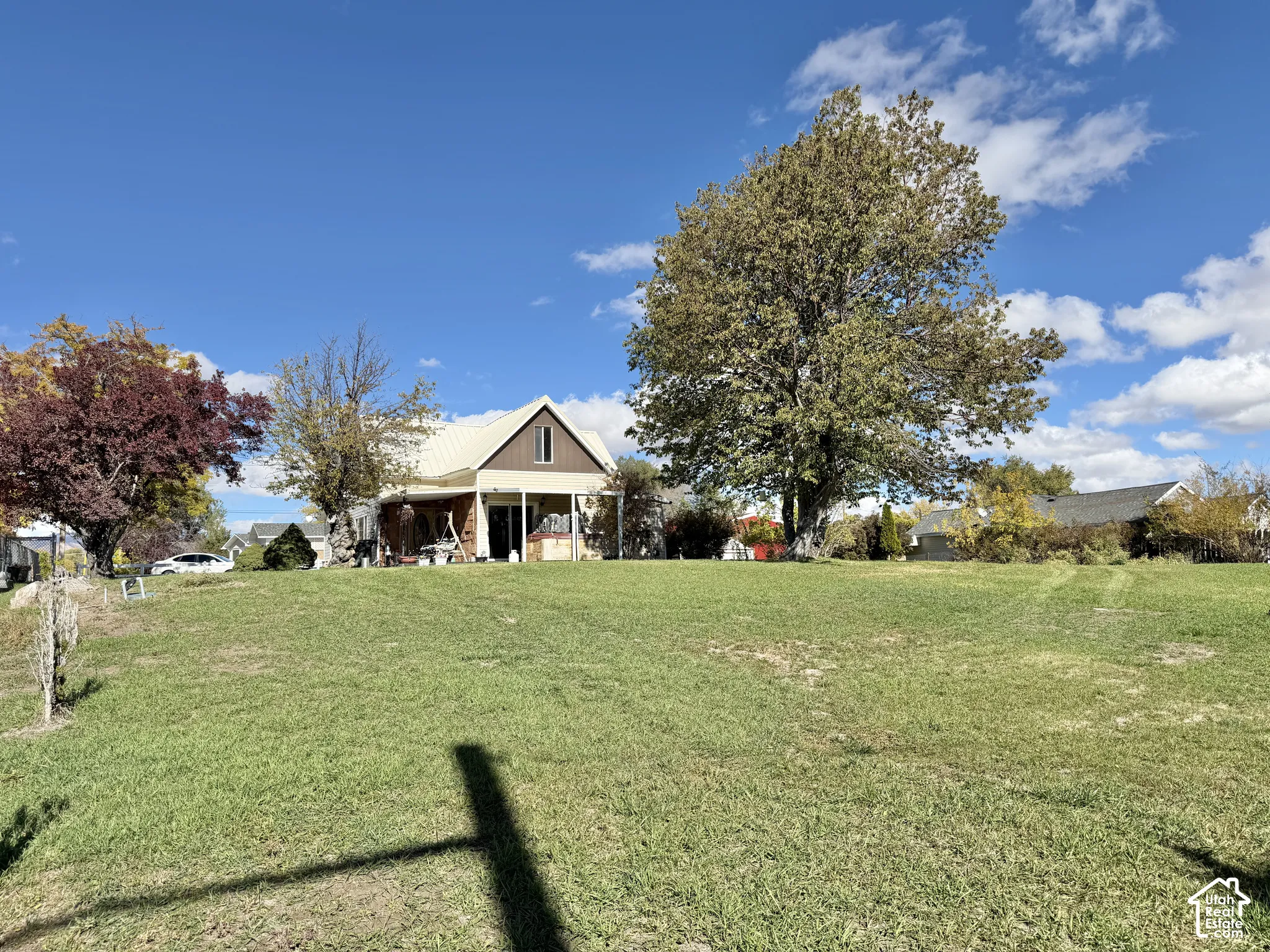 Expansive grounds featuring a spacious lawn, mature trees, a covered porch, and a metal roof