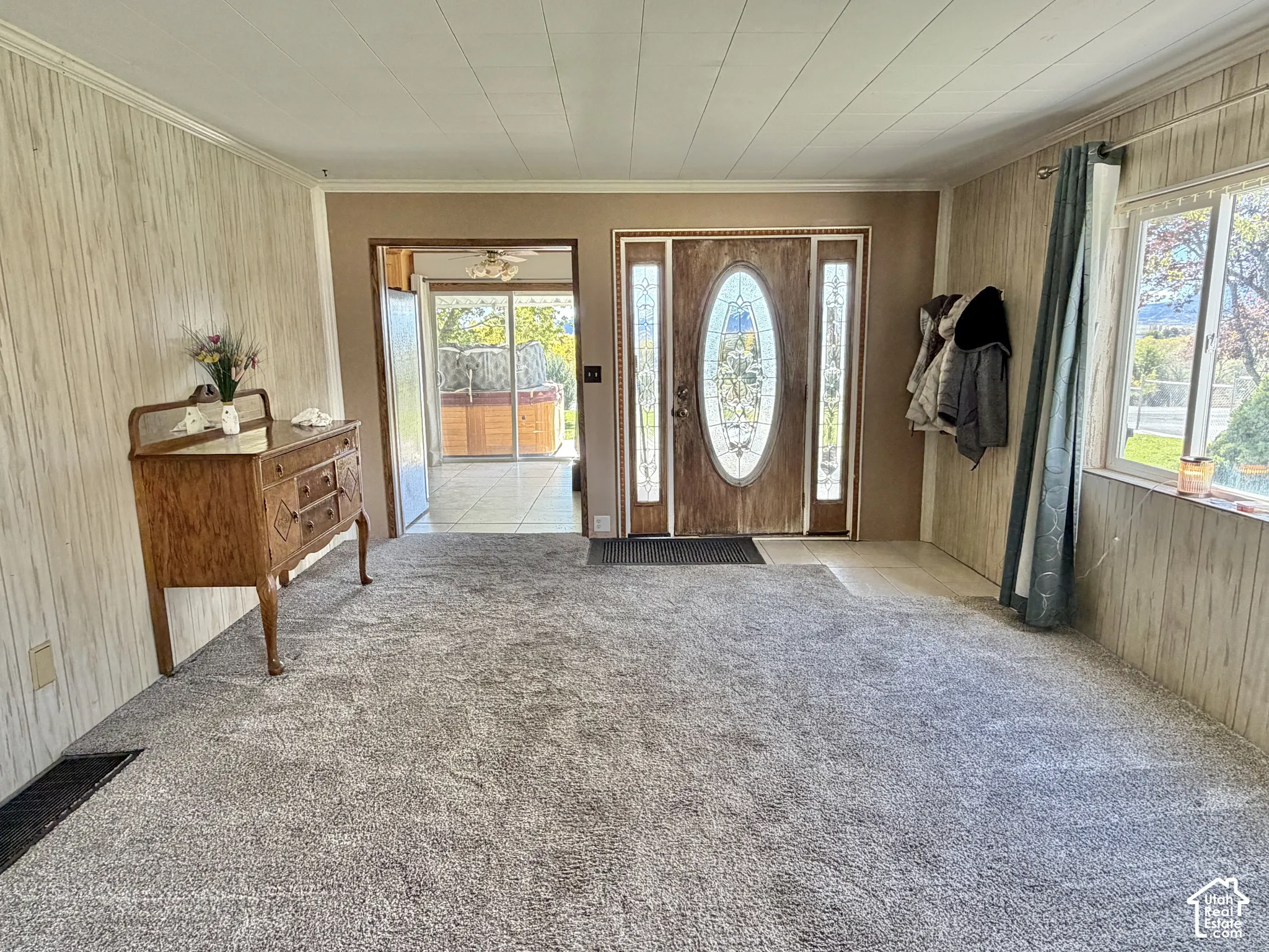 Entry featuring a wood-toned door with an oval glass insert and sidelights, wall-to-wall carpeting, and sliding glass doors